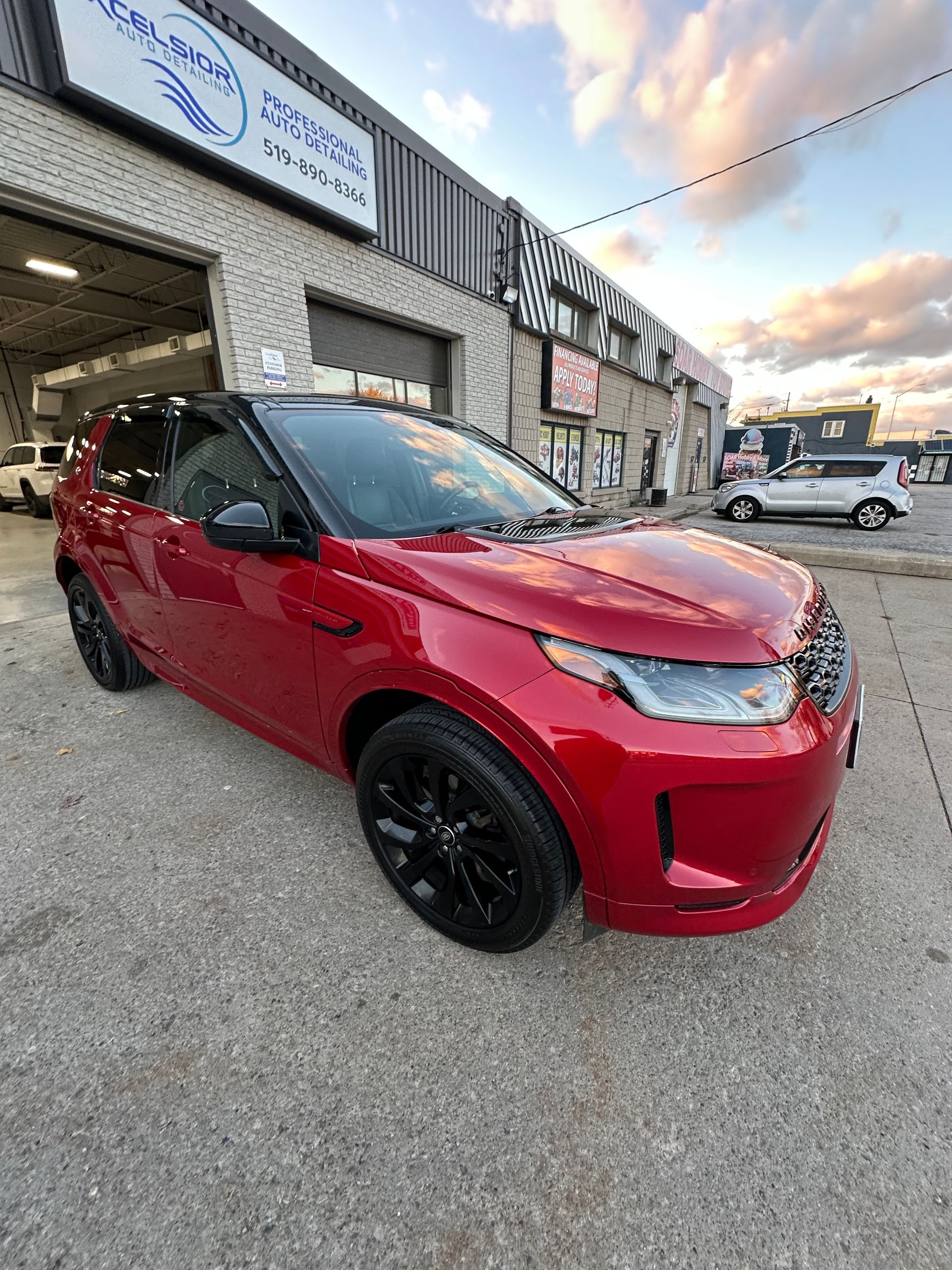 Red SUV parked outside an auto shop at sunset