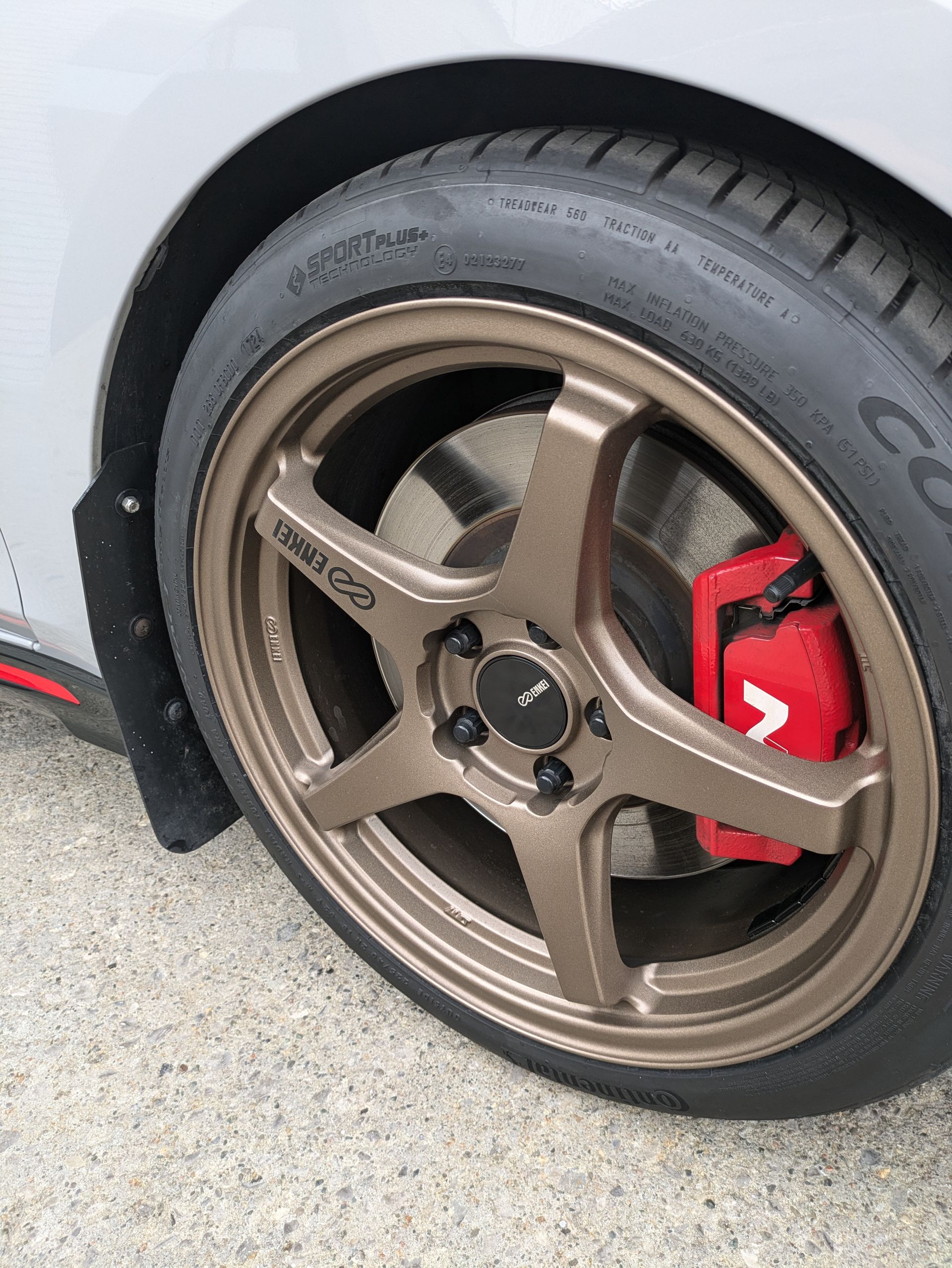 A close up of a car wheel with a red brake pad.