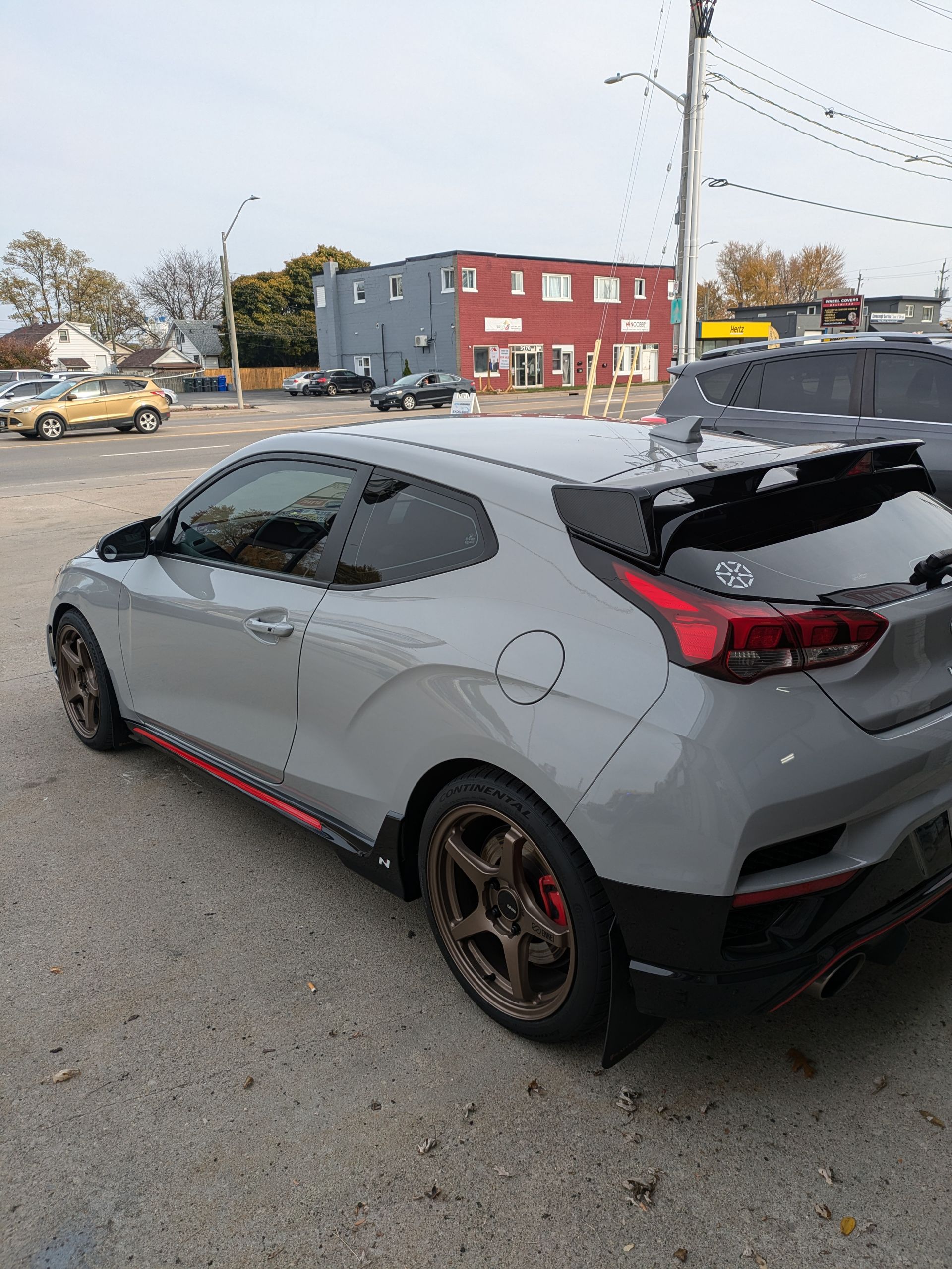 A gray car is parked in a parking lot in front of a building.