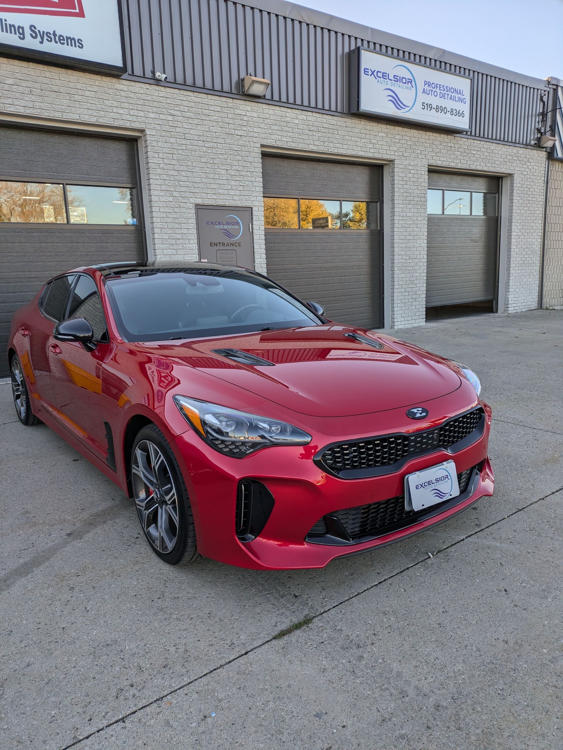 A red car is parked in front of a building.