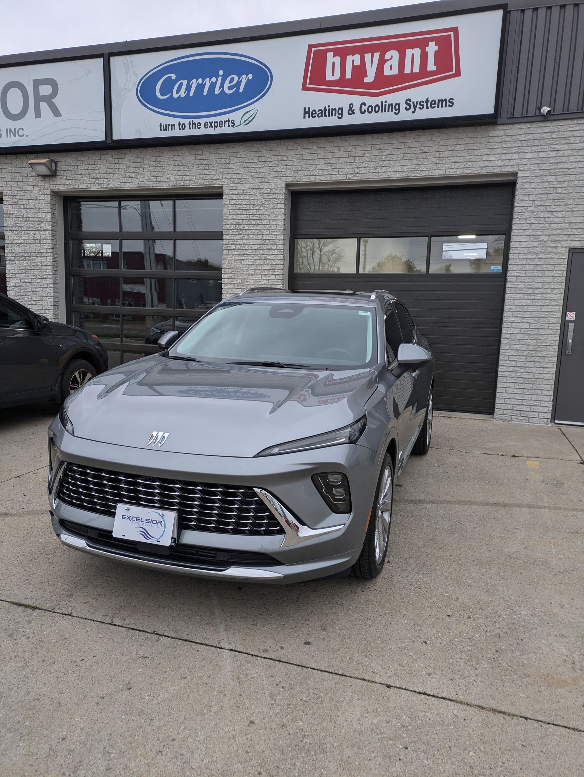 A gray car is parked in front of a building.