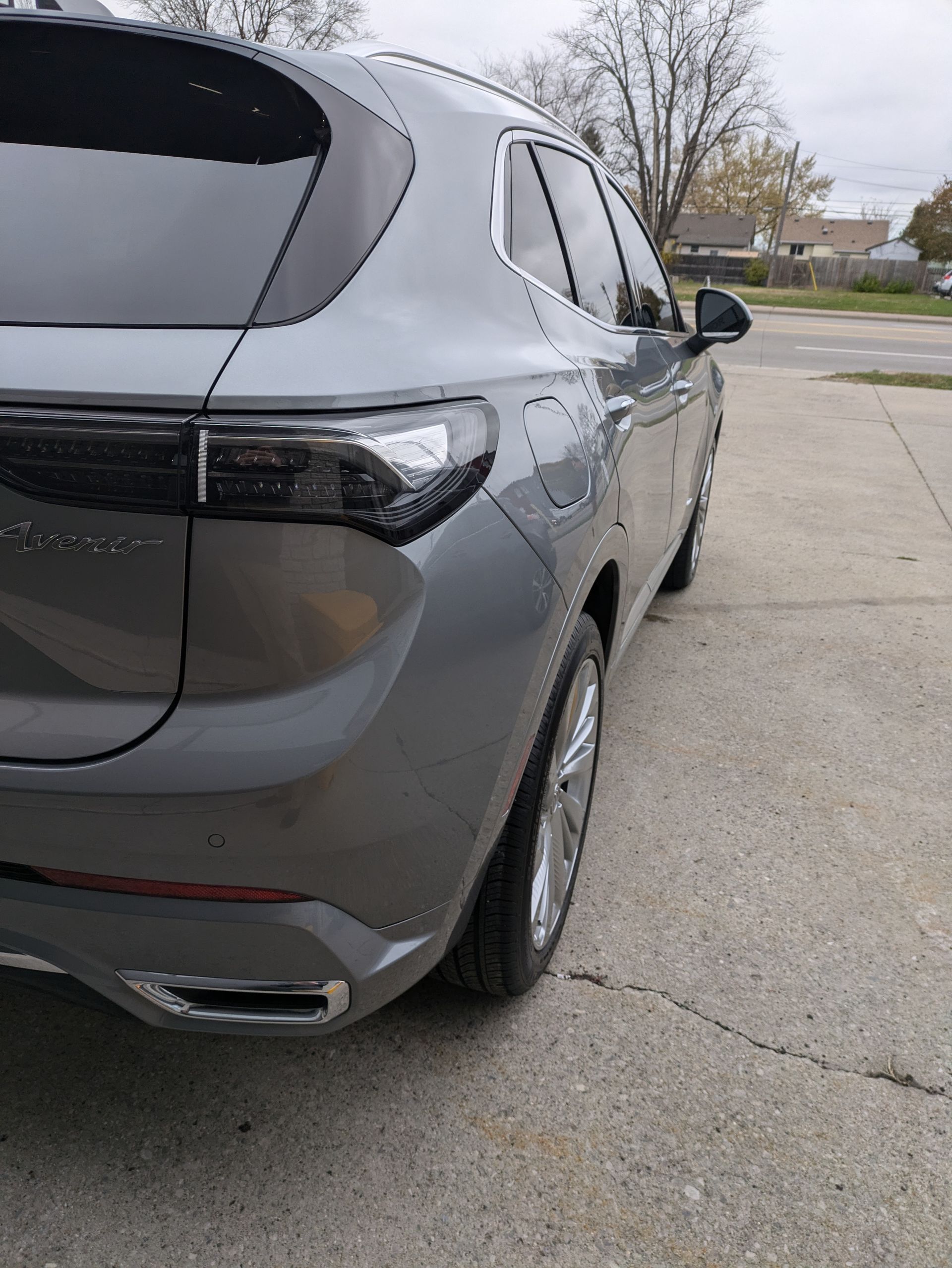 A gray car is parked on the side of the road.