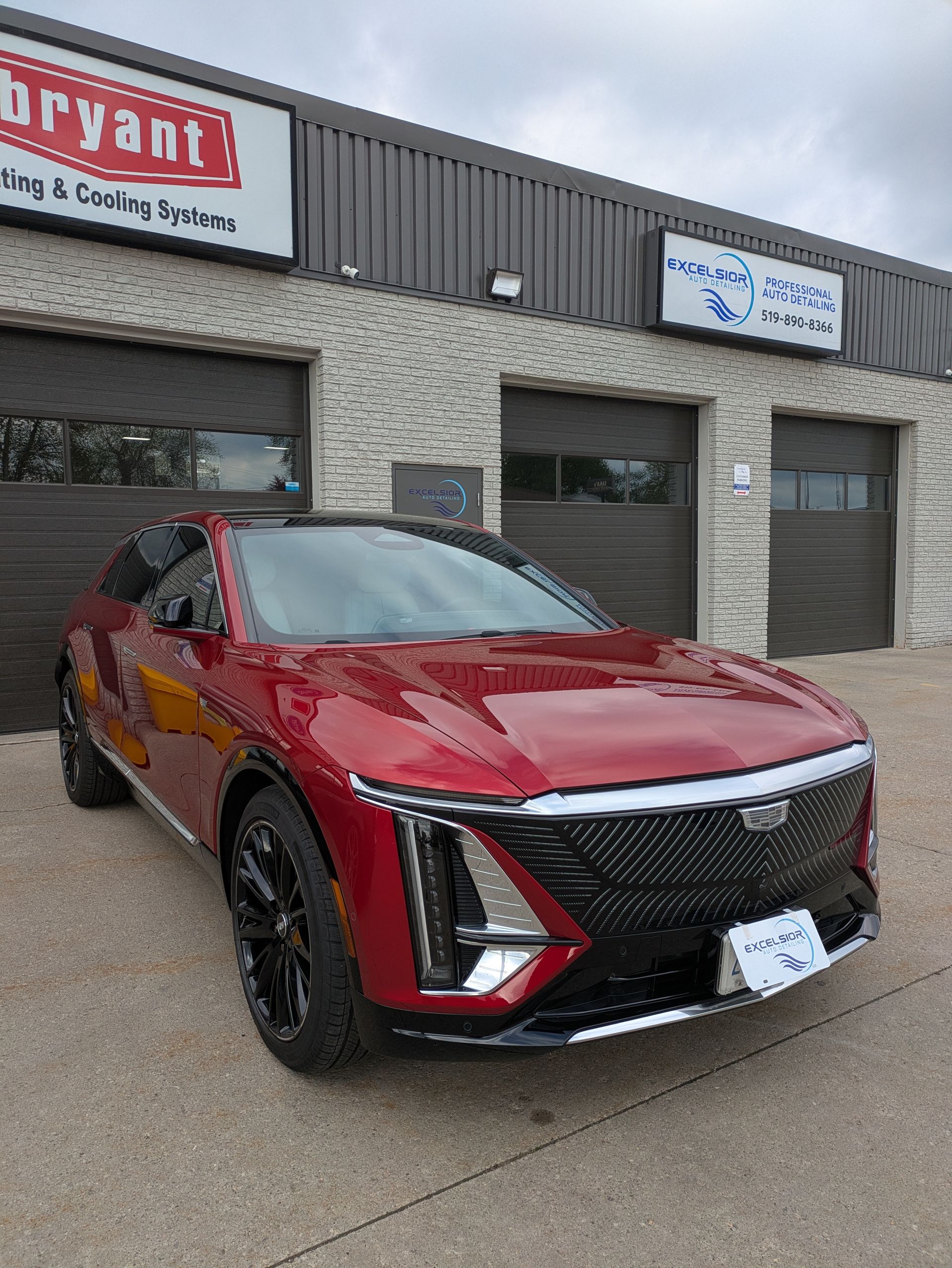 Red Cadillac SUV parked in front of a building with a Bryant sign and garage doors.