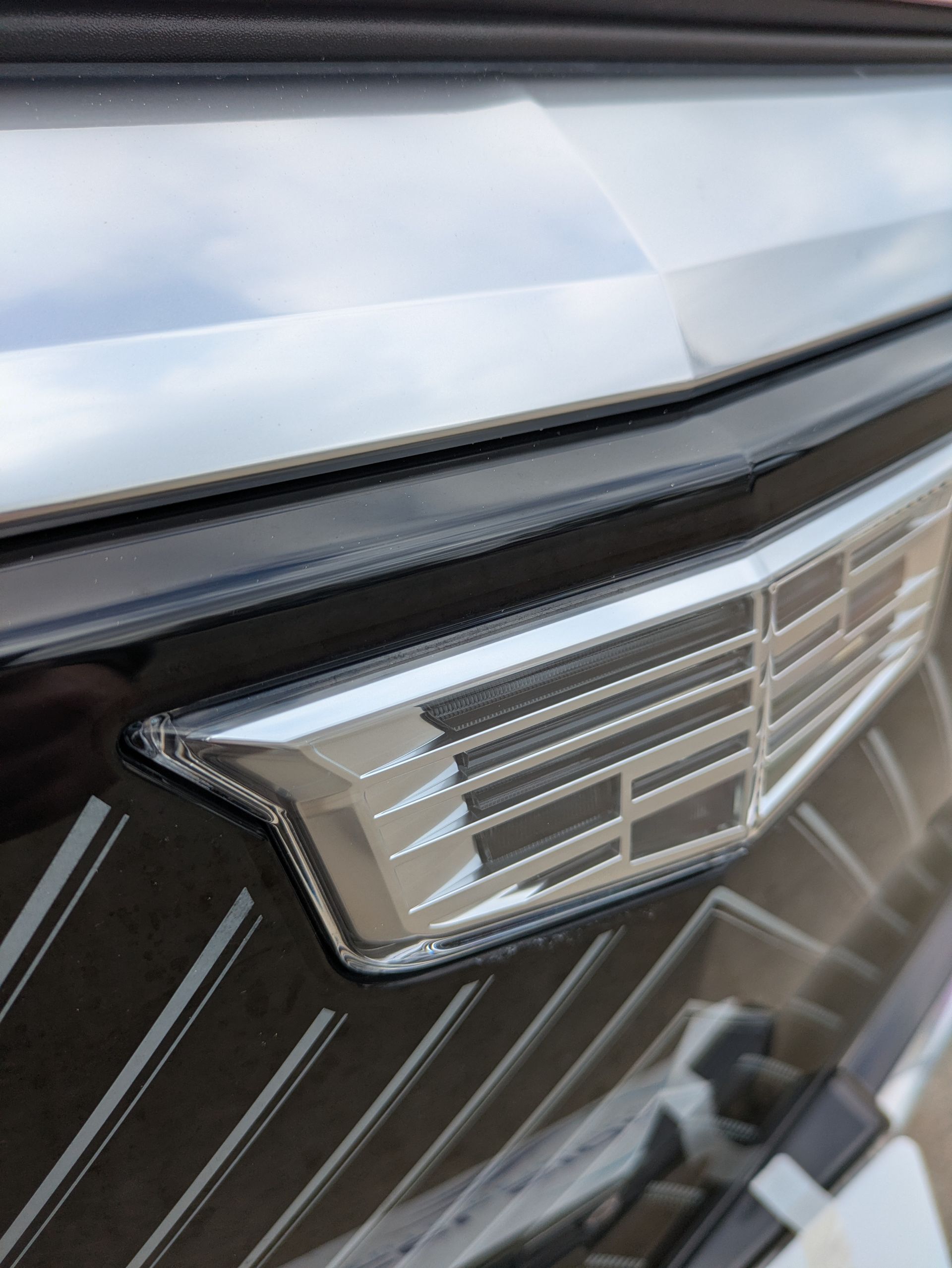 Close-up of a chrome Cadillac emblem on a black and silver car grille.