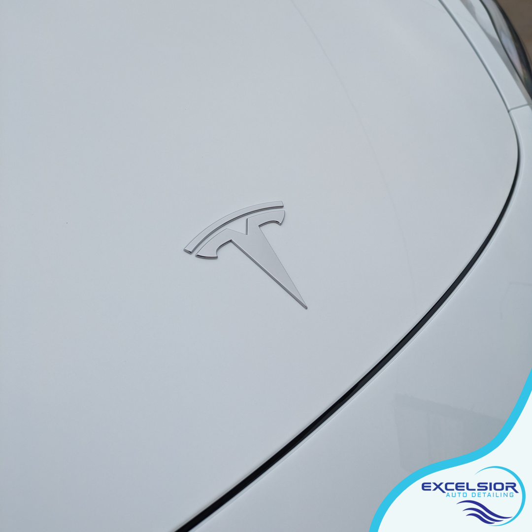 A white tesla with the letter t on the hood