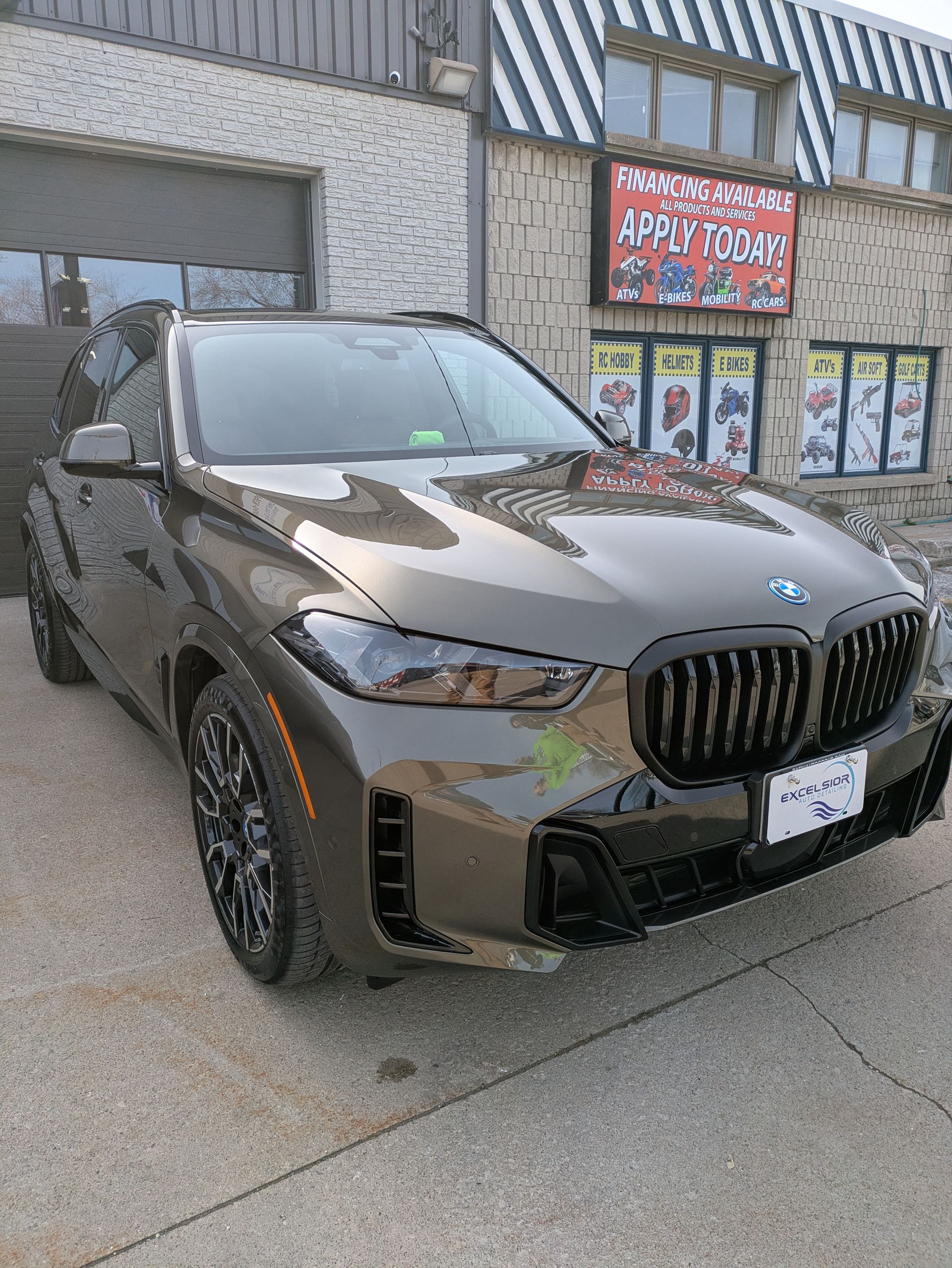 A bmw x5 m is parked in front of a building.