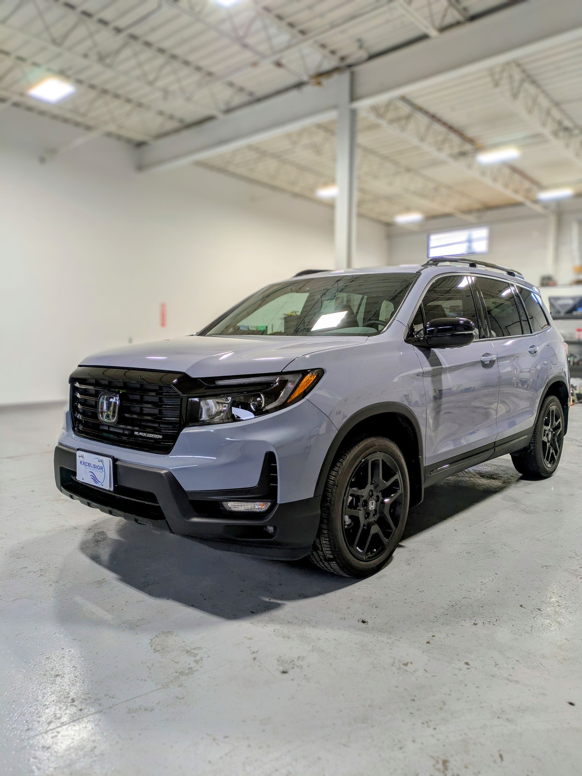 A gray honda ridgeline is parked in a garage.