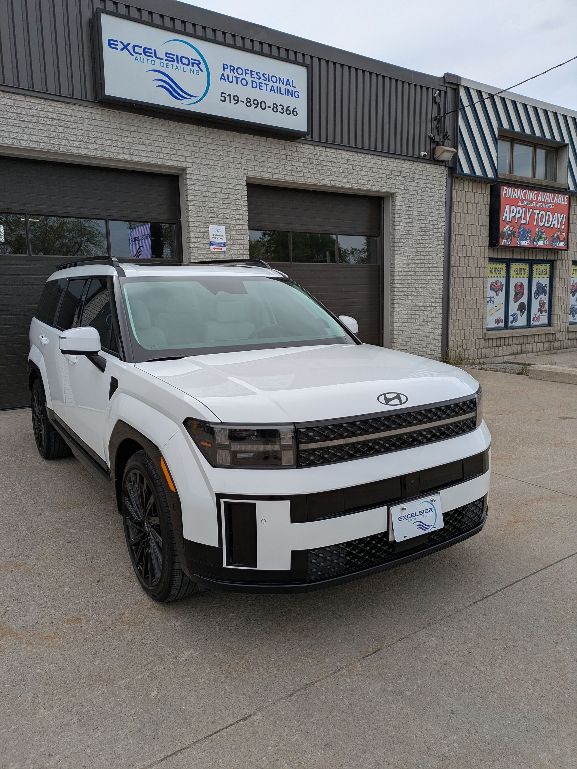 A white suv is parked in front of a building.