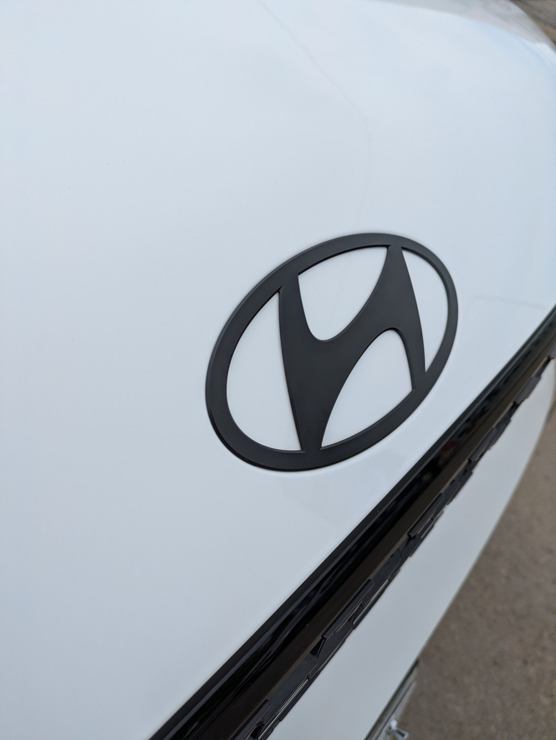 A white car with a black hyundai logo on the hood