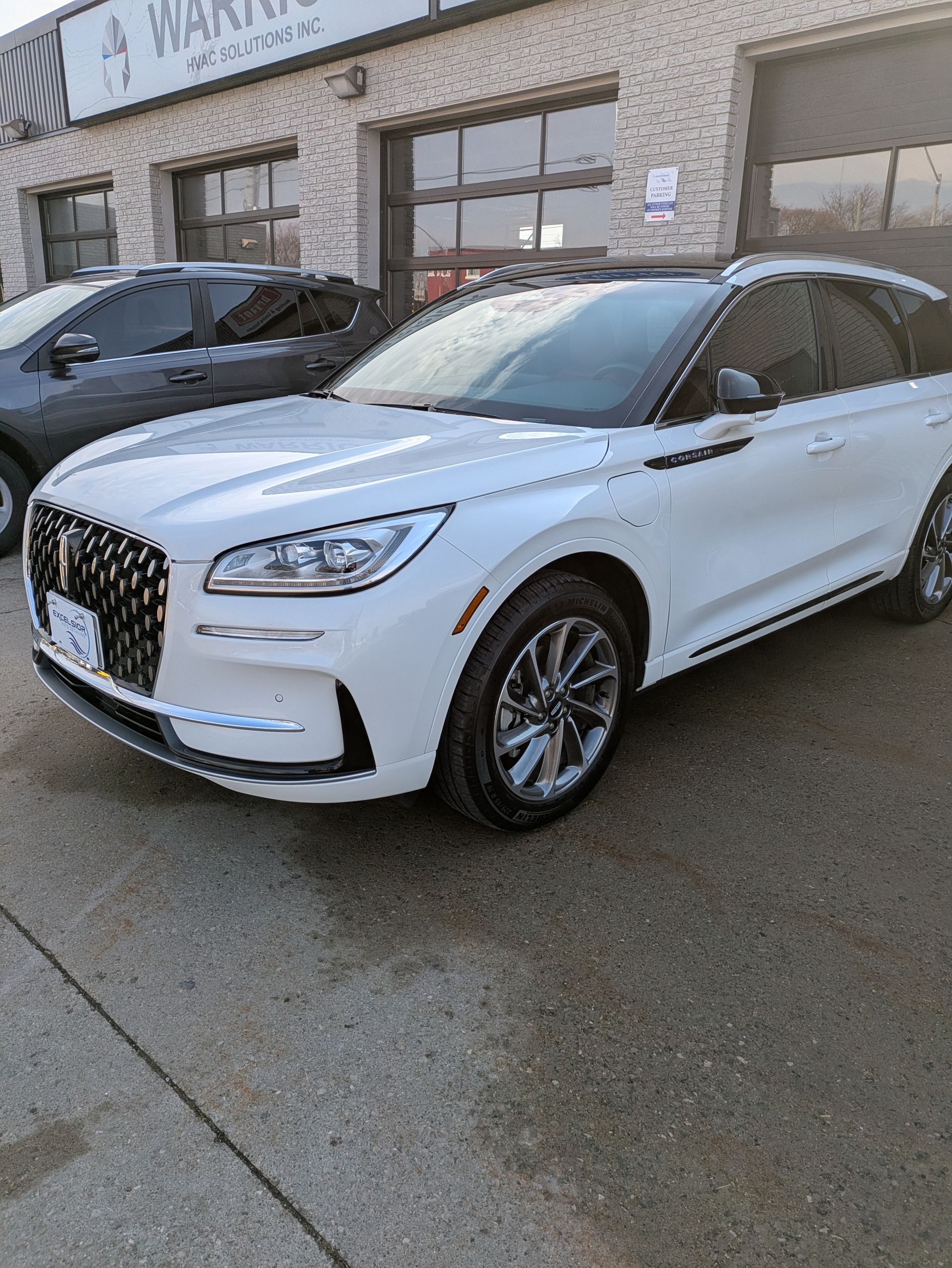 A white car is parked in front of a building.