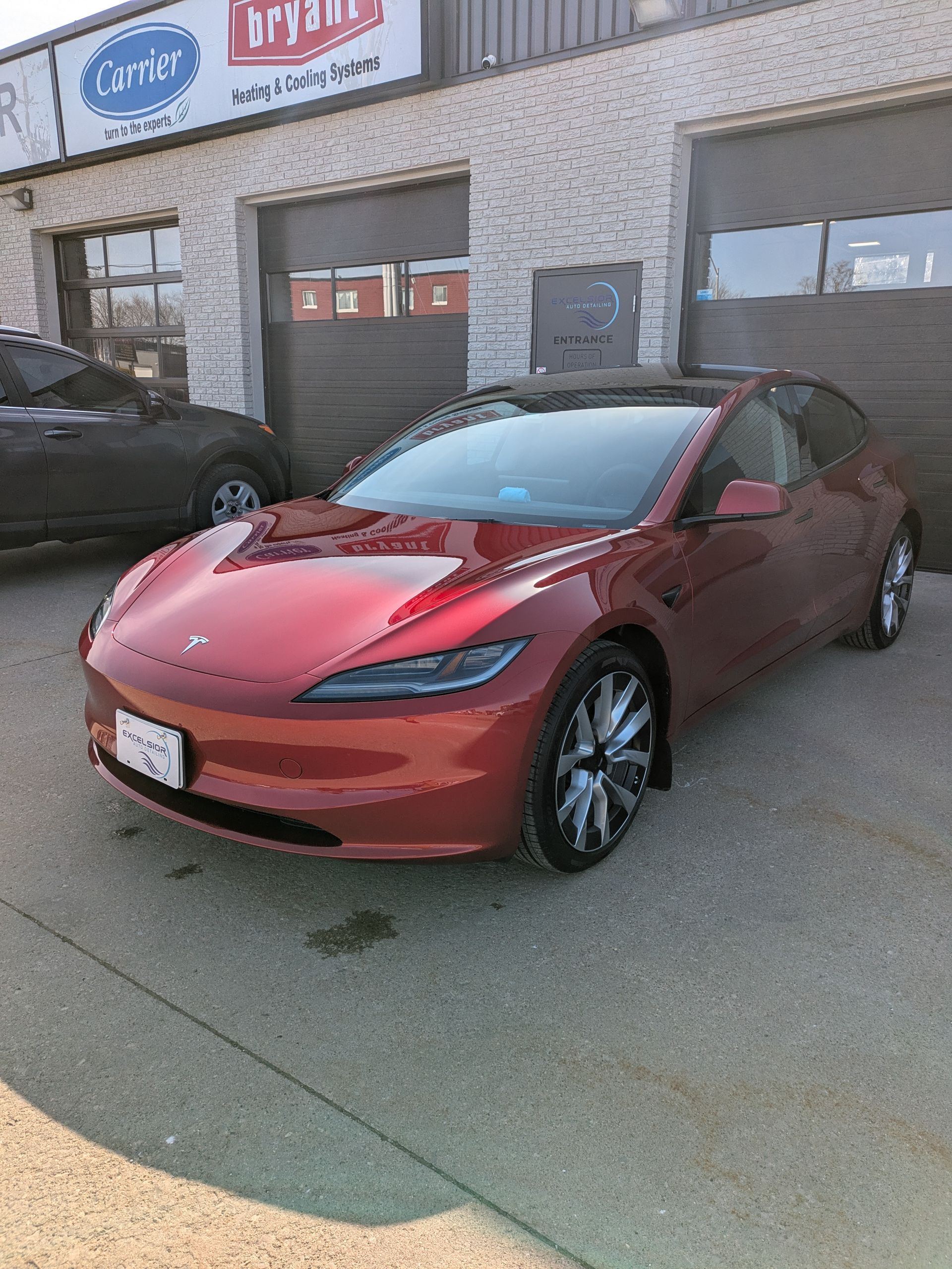 A red tesla model s is parked in front of a building.