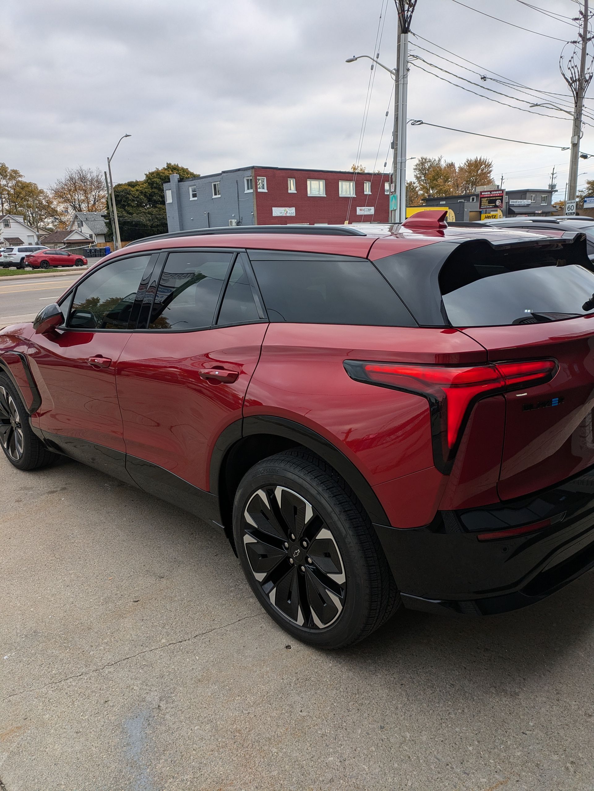 A red suv is parked in a parking lot in front of a building.