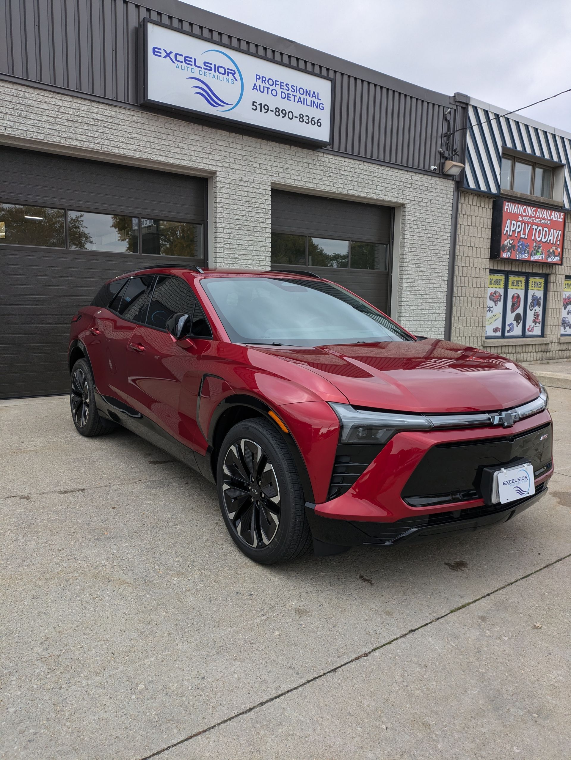 A red car is parked in front of a building.