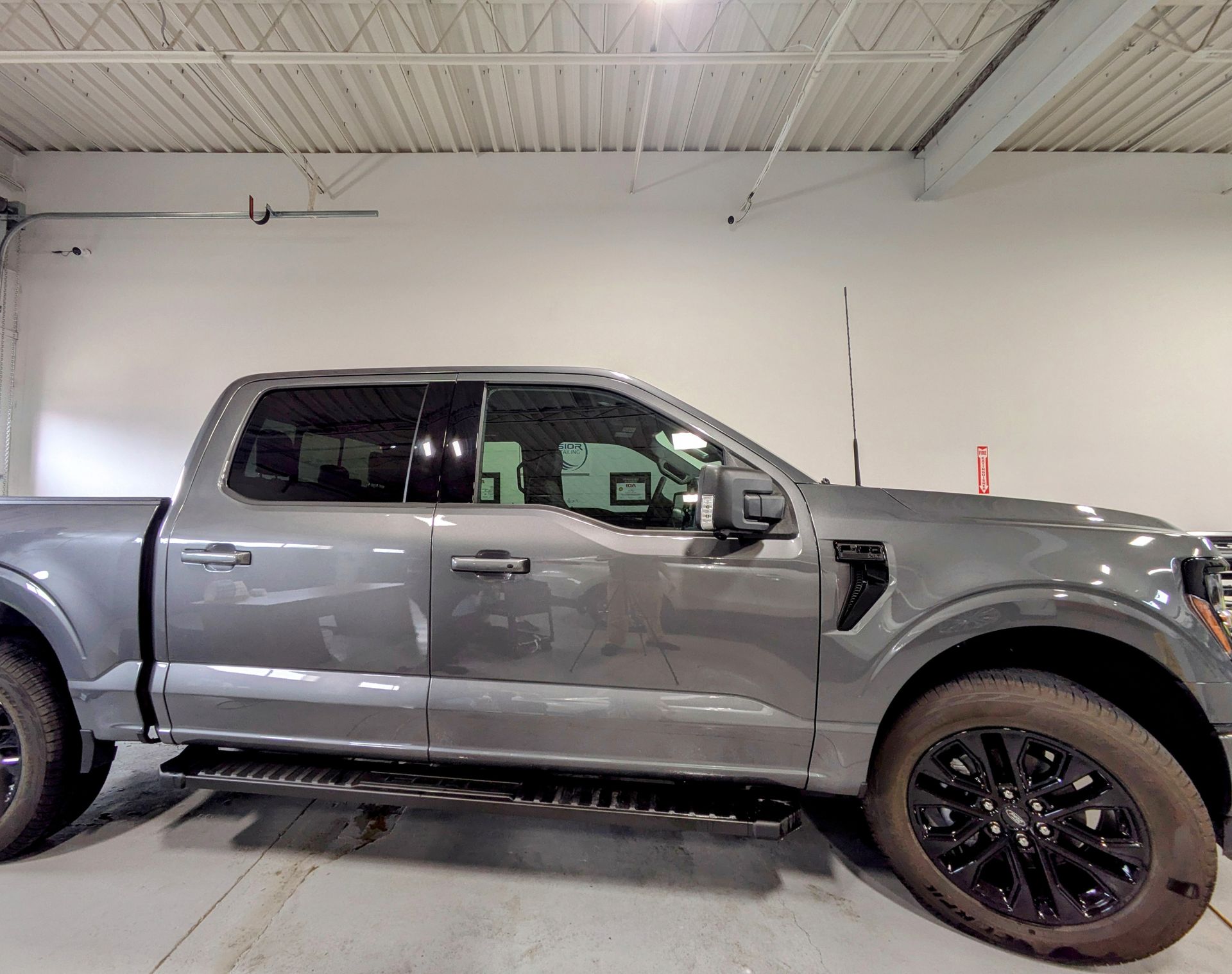 Gray pickup truck in a garage, side view with black wheels and tinted windows.