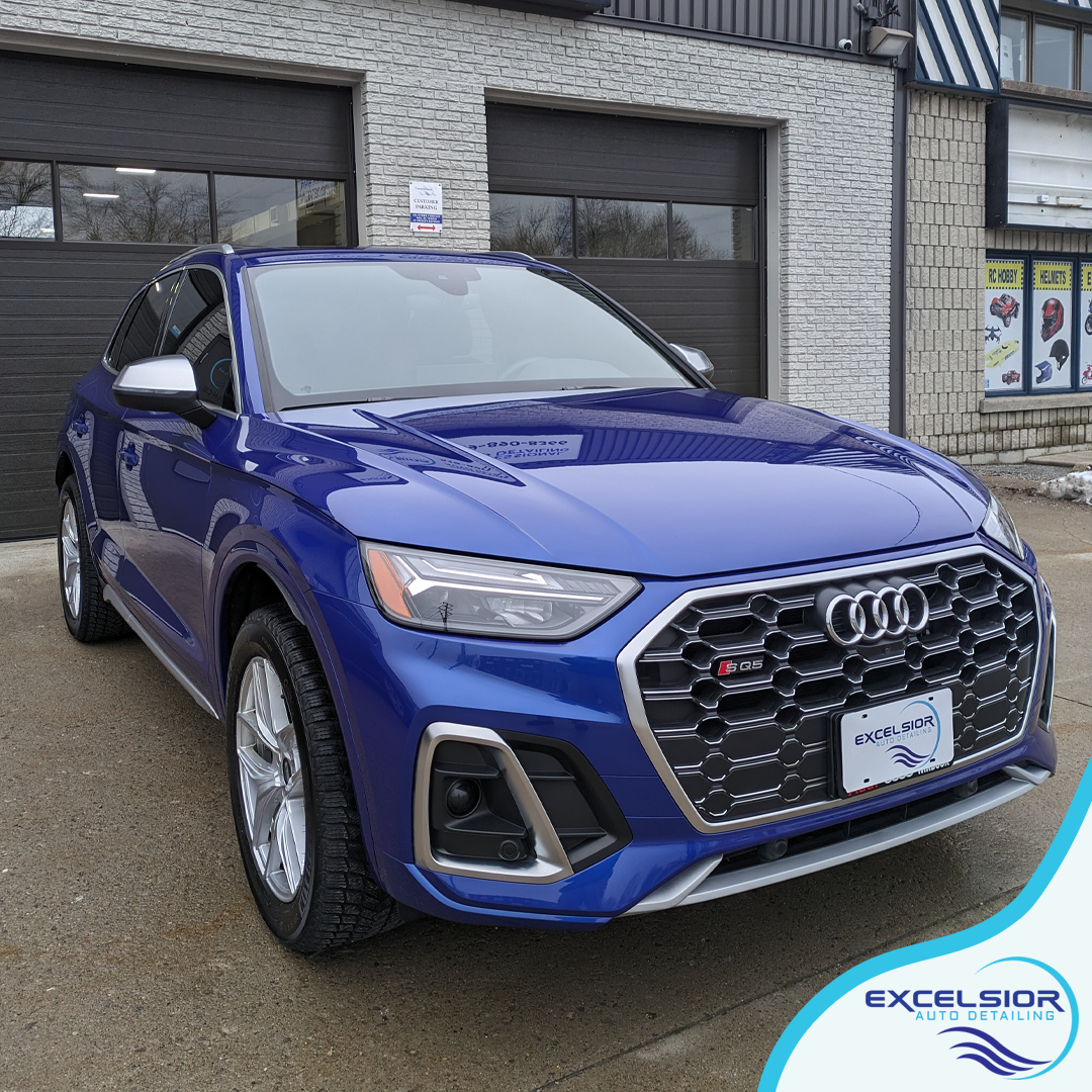 A blue audi q5 is parked in front of a garage door.