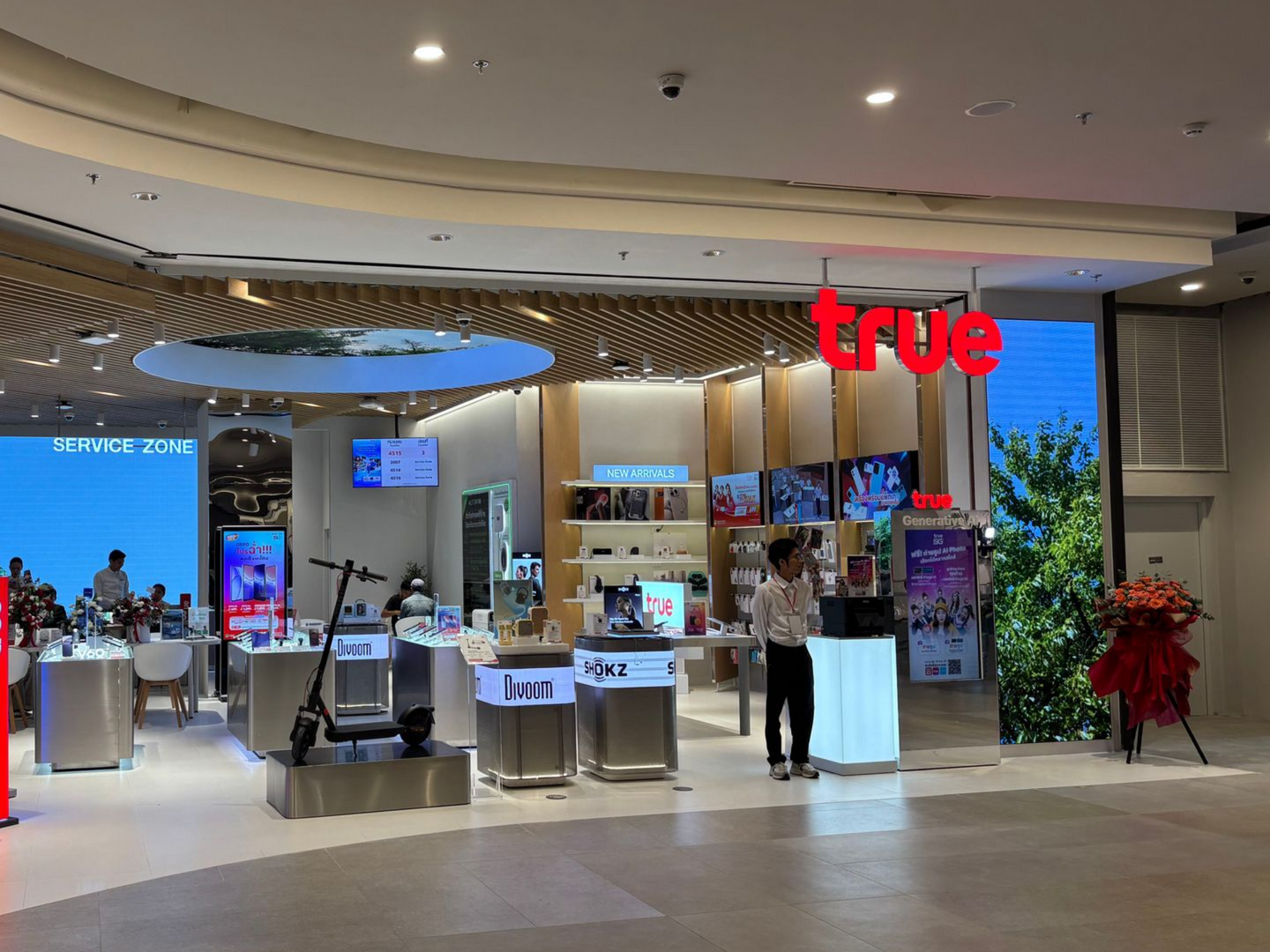True retail store counter in a mall with staff, displays, and a large red sign
