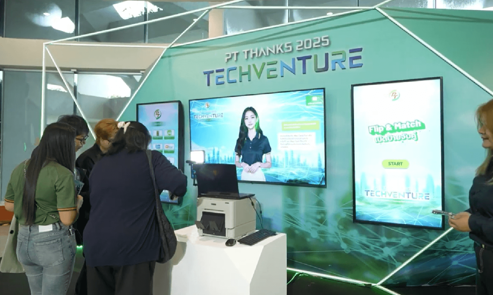 People viewing a TECHventure trade show booth with two large screens and a glowing green backdrop