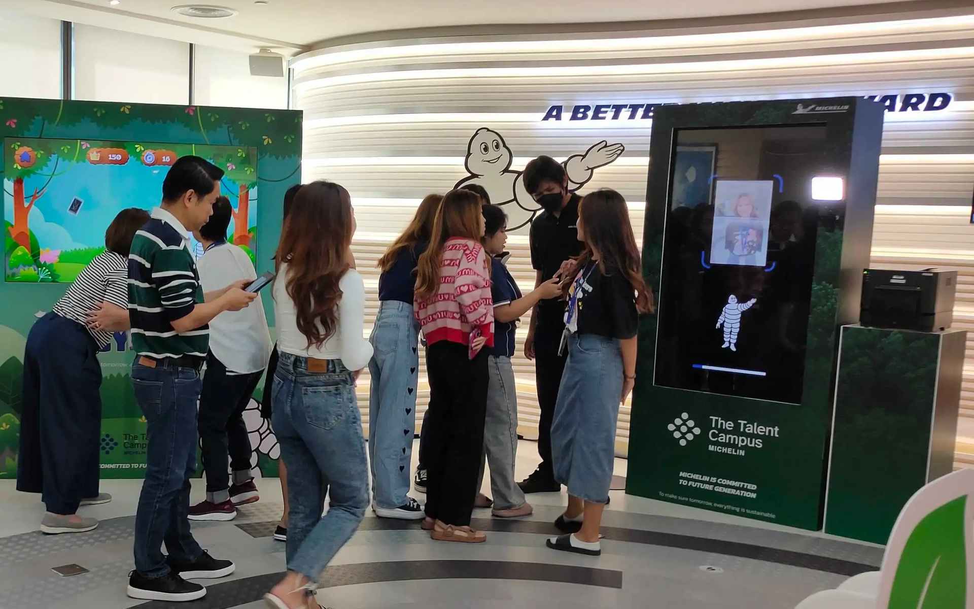 People gathered around a touchscreen kiosk in a bright indoor exhibit space.