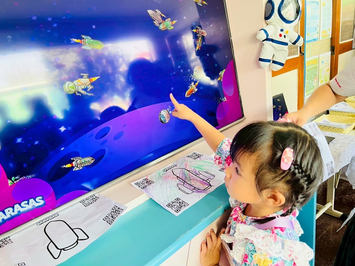 Child pointing at a colorful fish display in a classroom or museum exhibit.