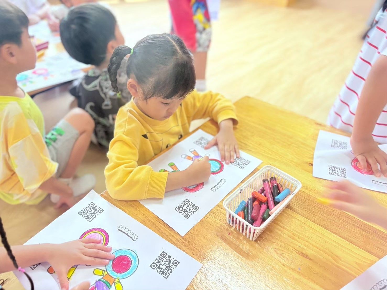 Children coloring at a table with crayons in a classroom setting