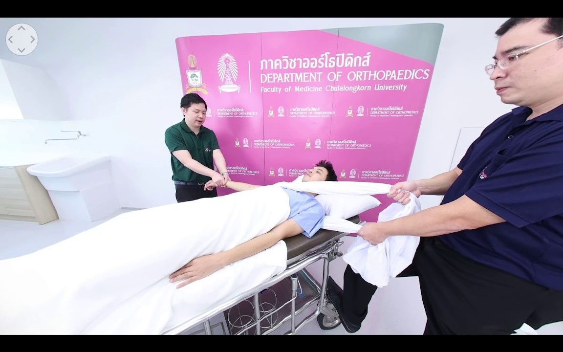 Clinic scene with a patient on a stretcher and staff handing over a white garment near a pink hospital sign.