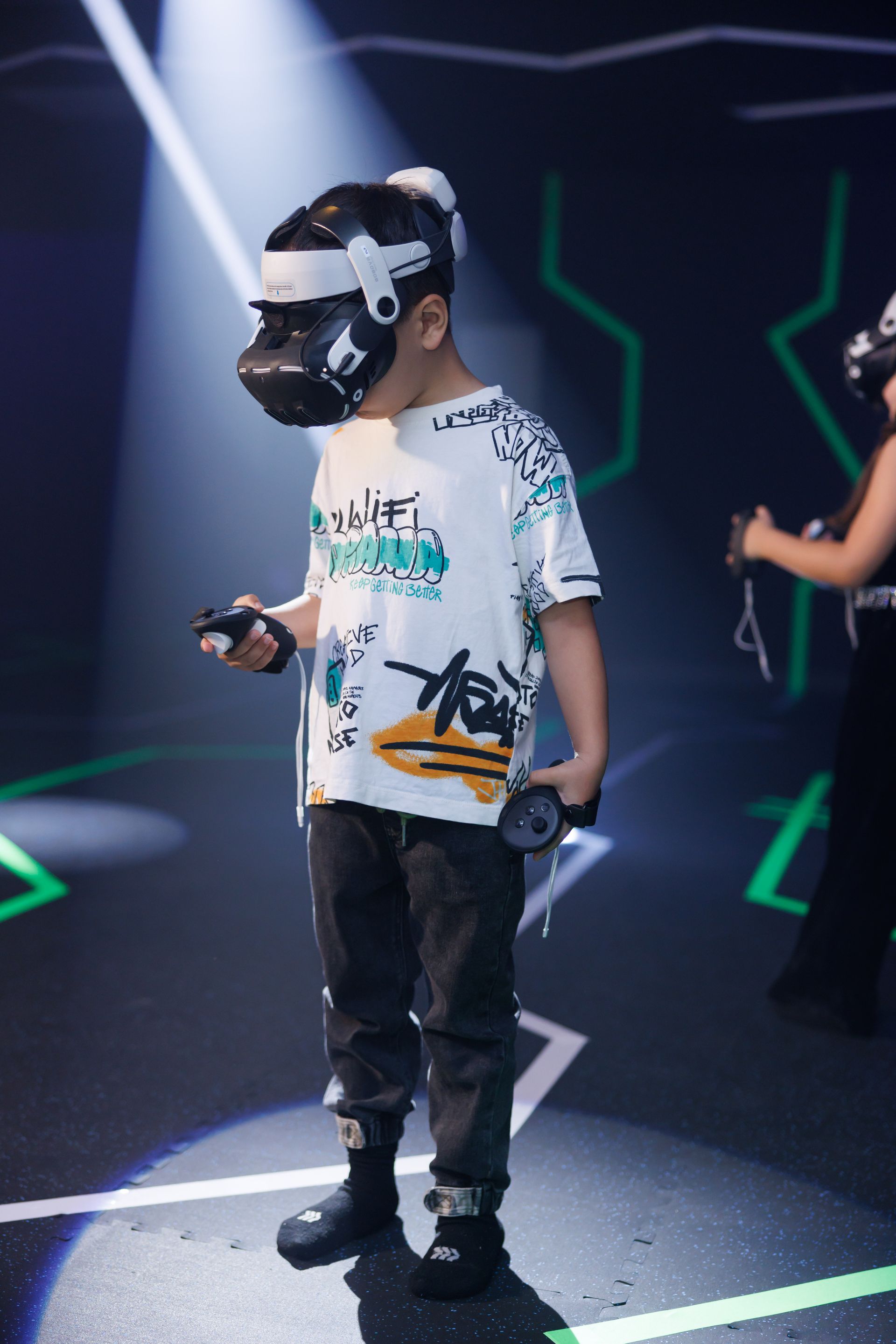 A person wearing a VR headset and holding controllers stands in a dark room with glowing green geometric light patterns.