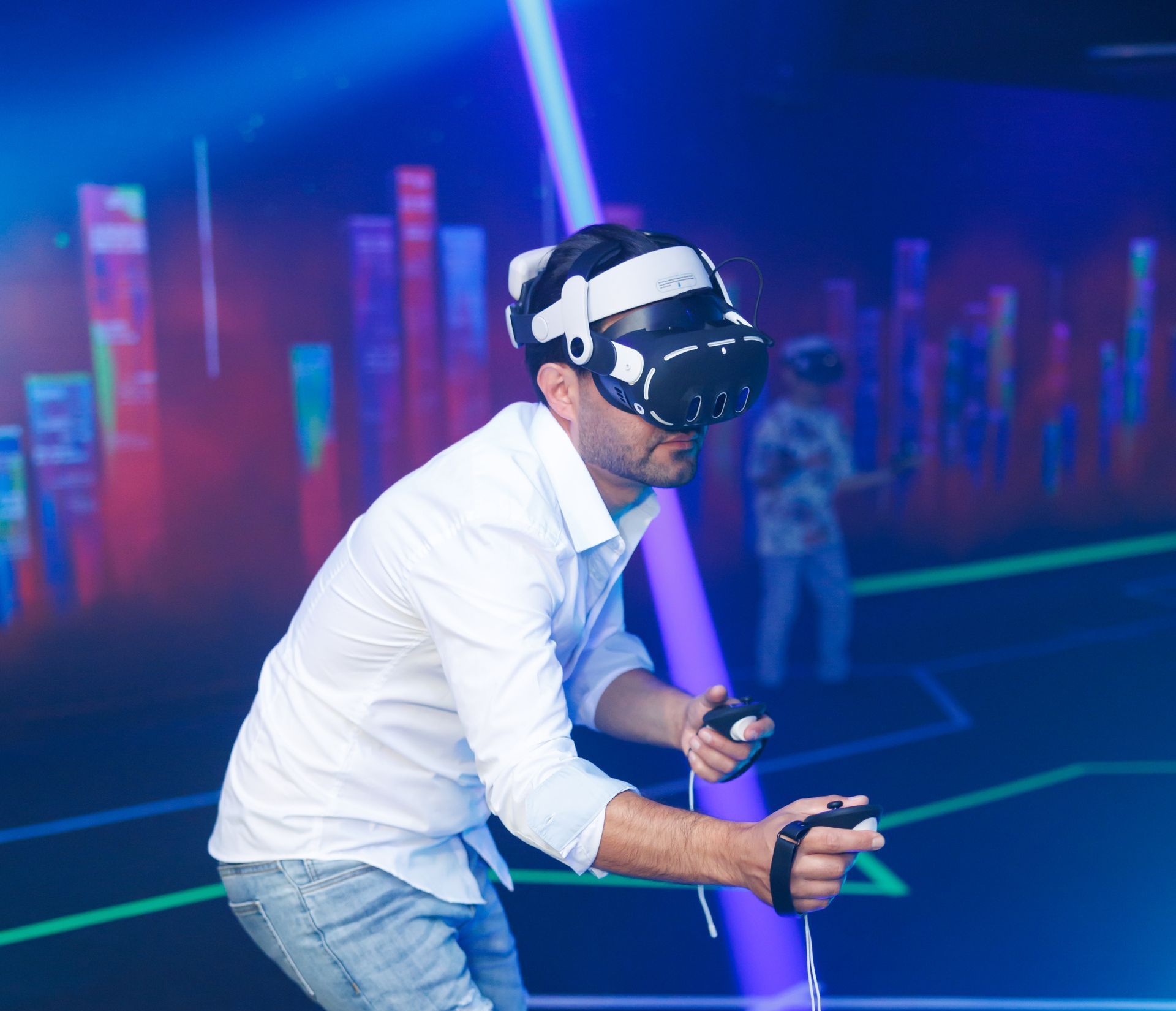 A person wearing a VR headset and holding controllers stands in a blue-lit room with abstract digital wall graphics.