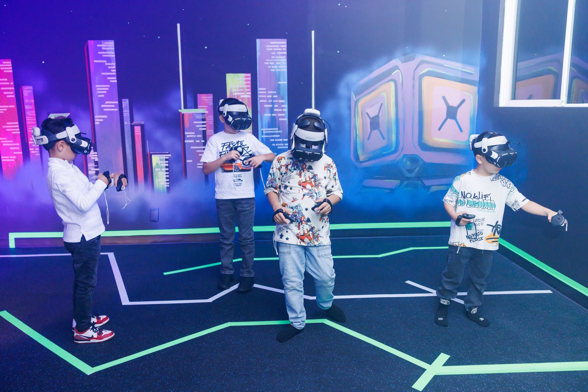 Four people wearing VR headsets stand in a dark room with glowing floor lines and a digital cityscape background.