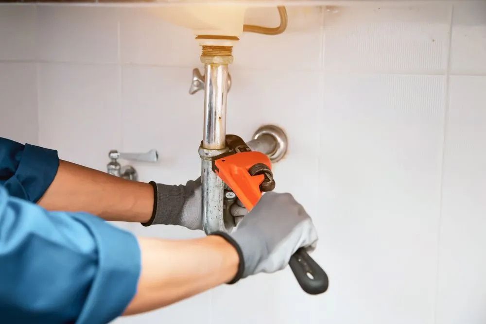 A Plumber is Fixing a Sink Pipe With a Wrench — Foreshore Plumbers In Tuncurry, NSW
