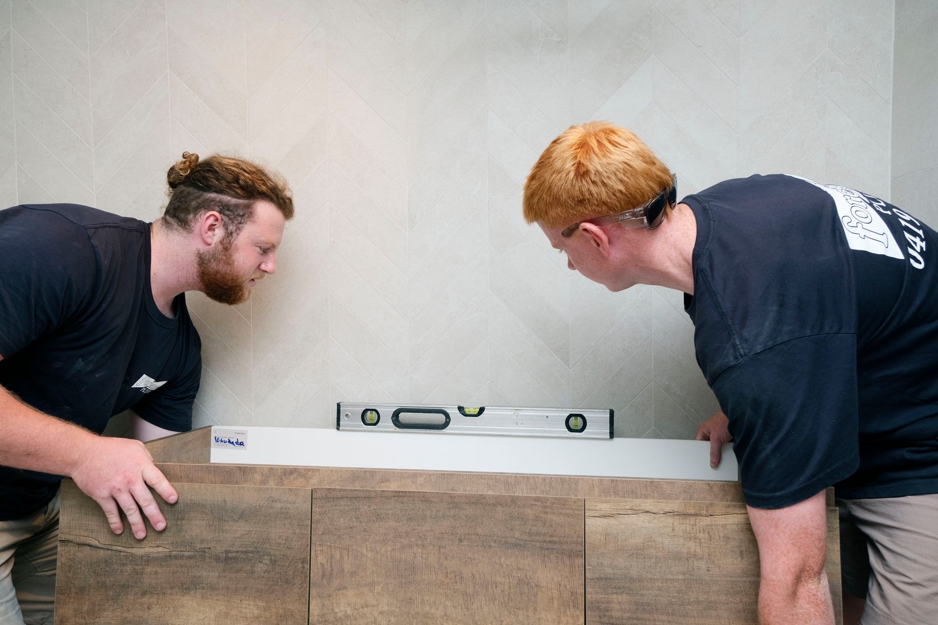 Two Men Are Measuring a Bathtub With a Level — Foreshore Plumbers In Hallidays Point, NSW