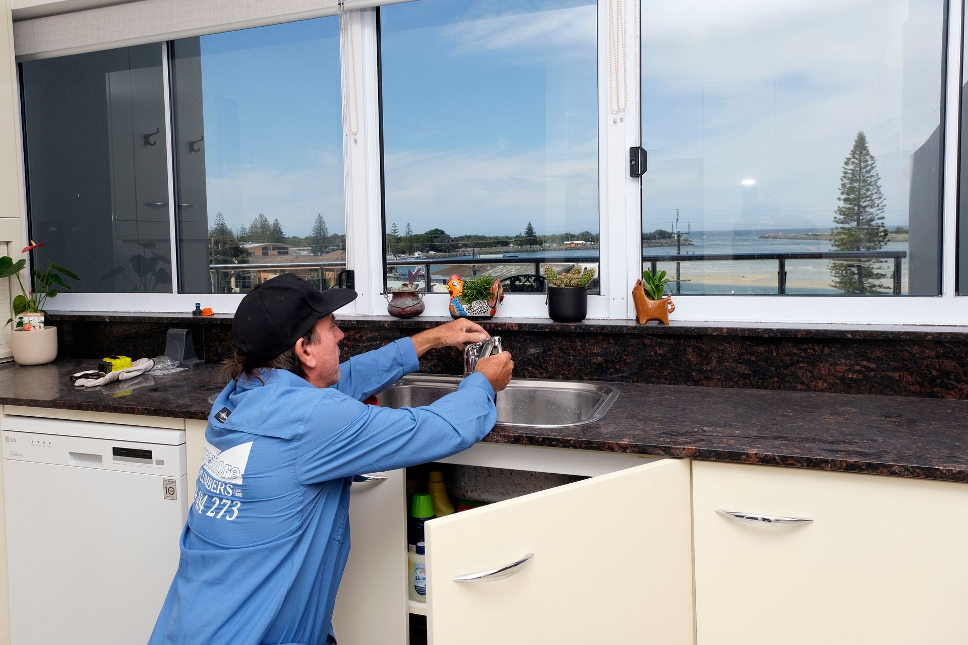 A Person is Fixing a Sink Faucet With Pliers — Foreshore Plumbers in Tuncurry, NSW