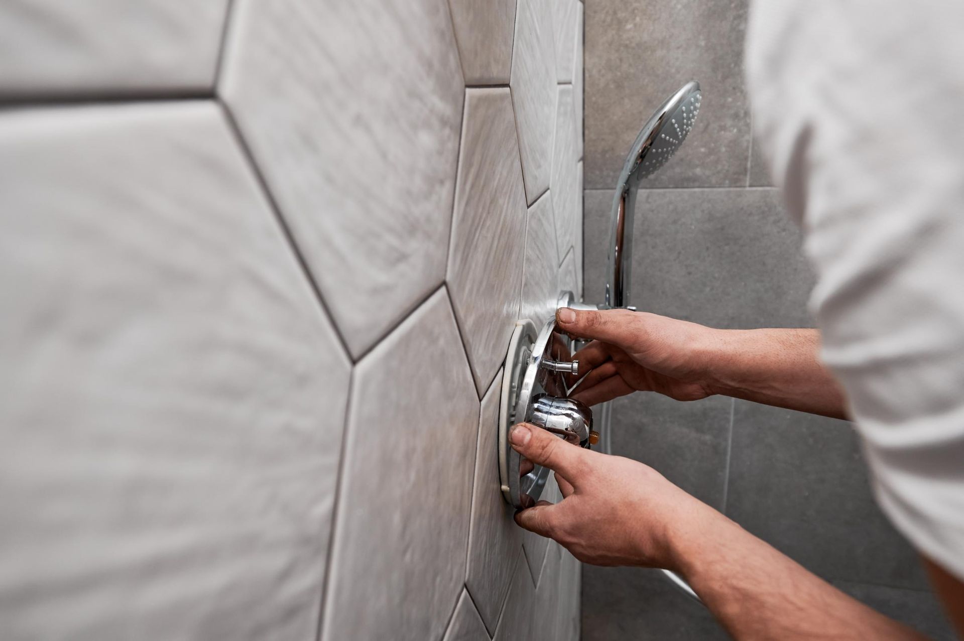 A Man is Fixing a Shower Head in a Bathroom — Foreshore Plumbers In Tuncurry, NSW