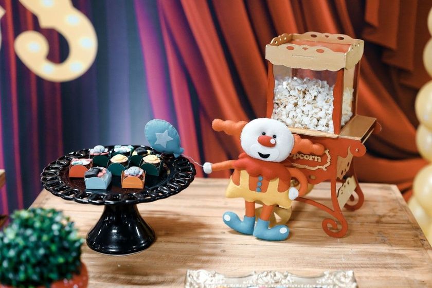 Miniature candy cart and tray on a wooden table, with a smiling toy figure in a festive display