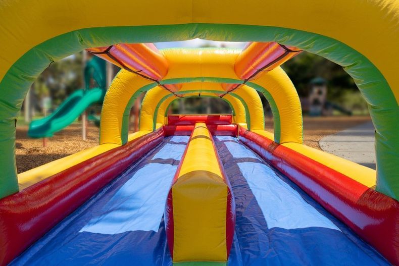 Colorful inflatable obstacle course with red, blue, yellow, and green tunnels outdoors