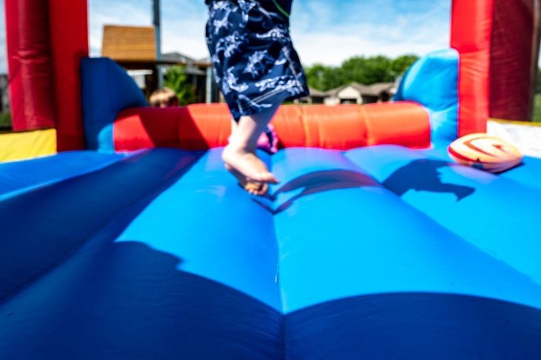 Child jumping on a blue inflatable bounce house outdoors