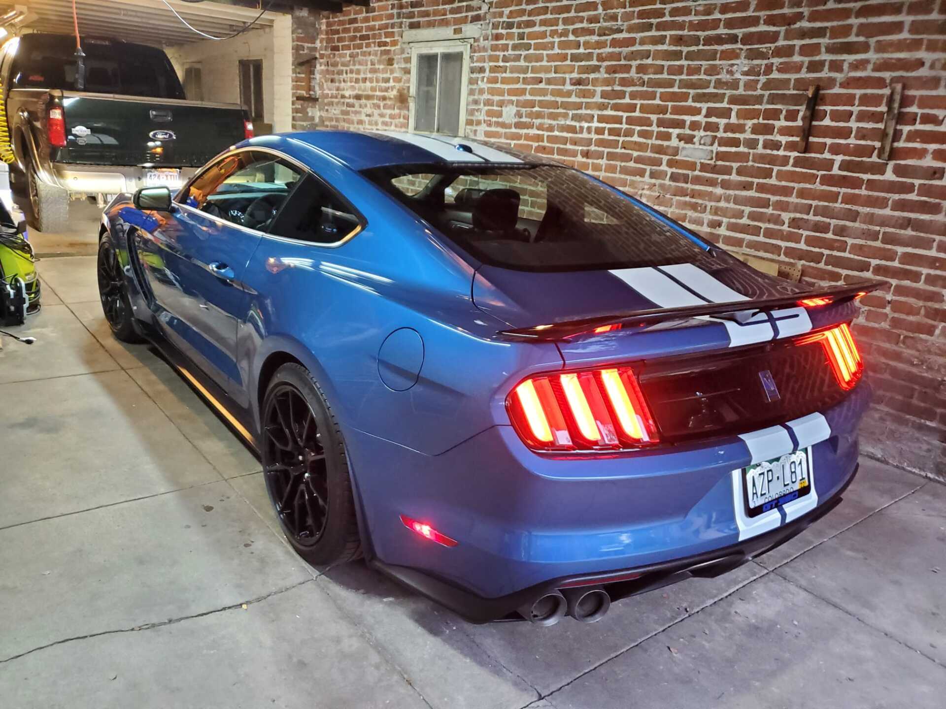a blue mustang parked in a garage next to a brick wall .