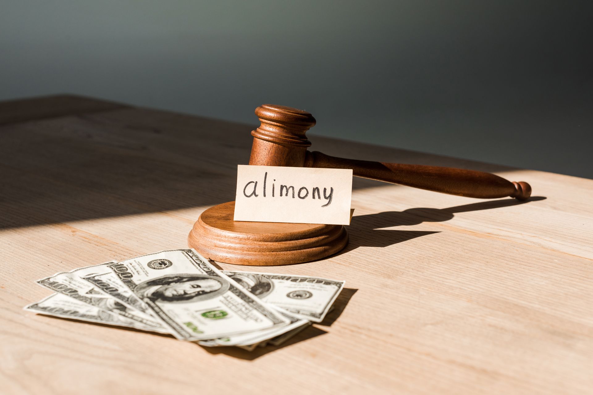 Judge’s gavel beside cash and a note labeled alimony, representing financial support after divorce.