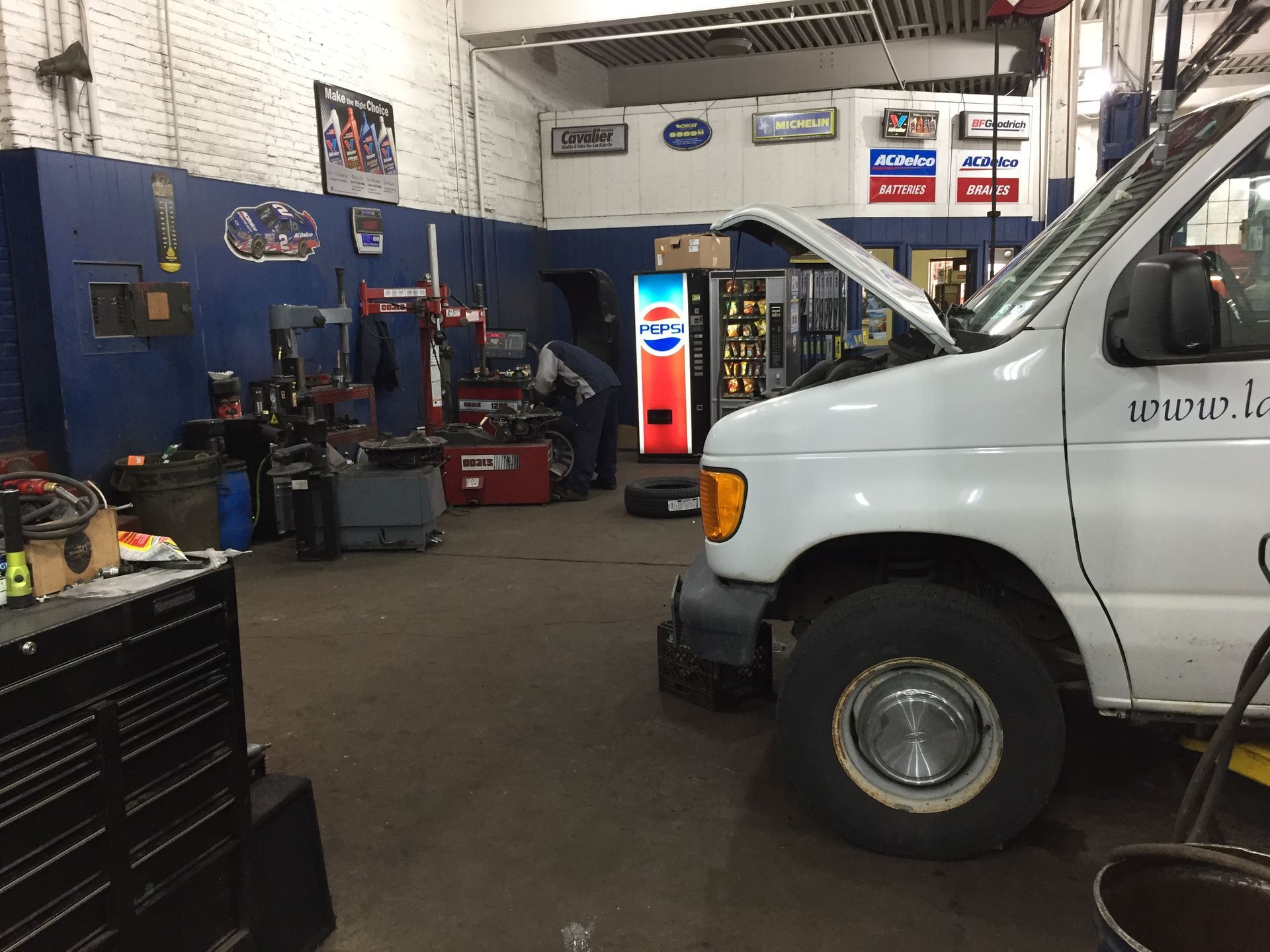 Auto repair shop interior with a white van, tool chest, and soda machine.