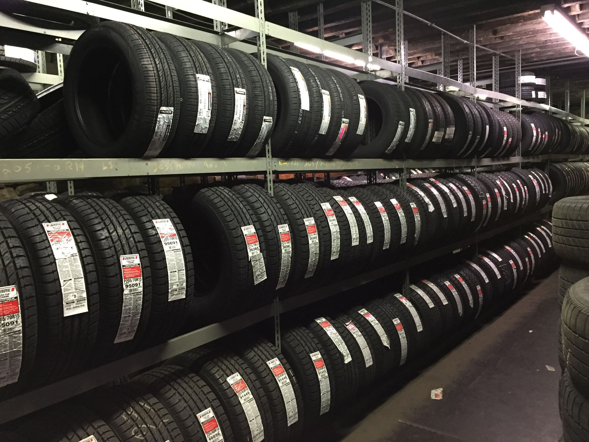 Stacks of black tires stored on metal racks in a warehouse or tire shop.