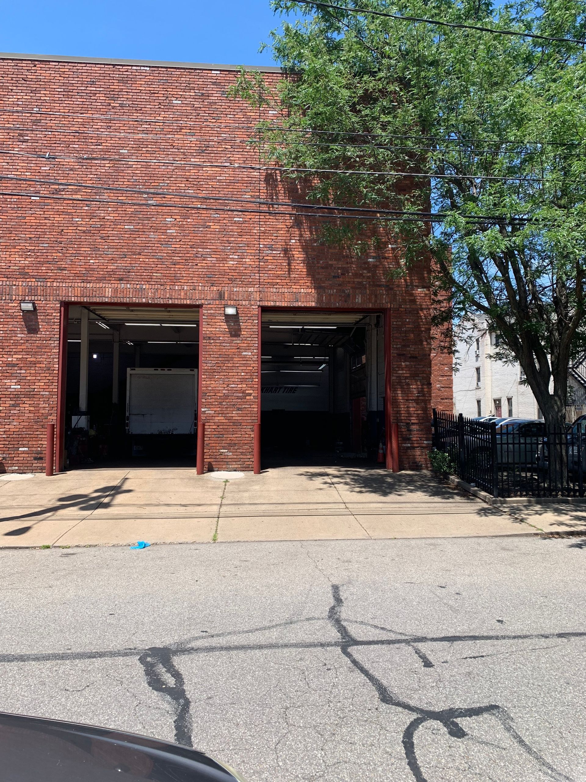 Brick building with two open garage doors and a tree beside the entrance.