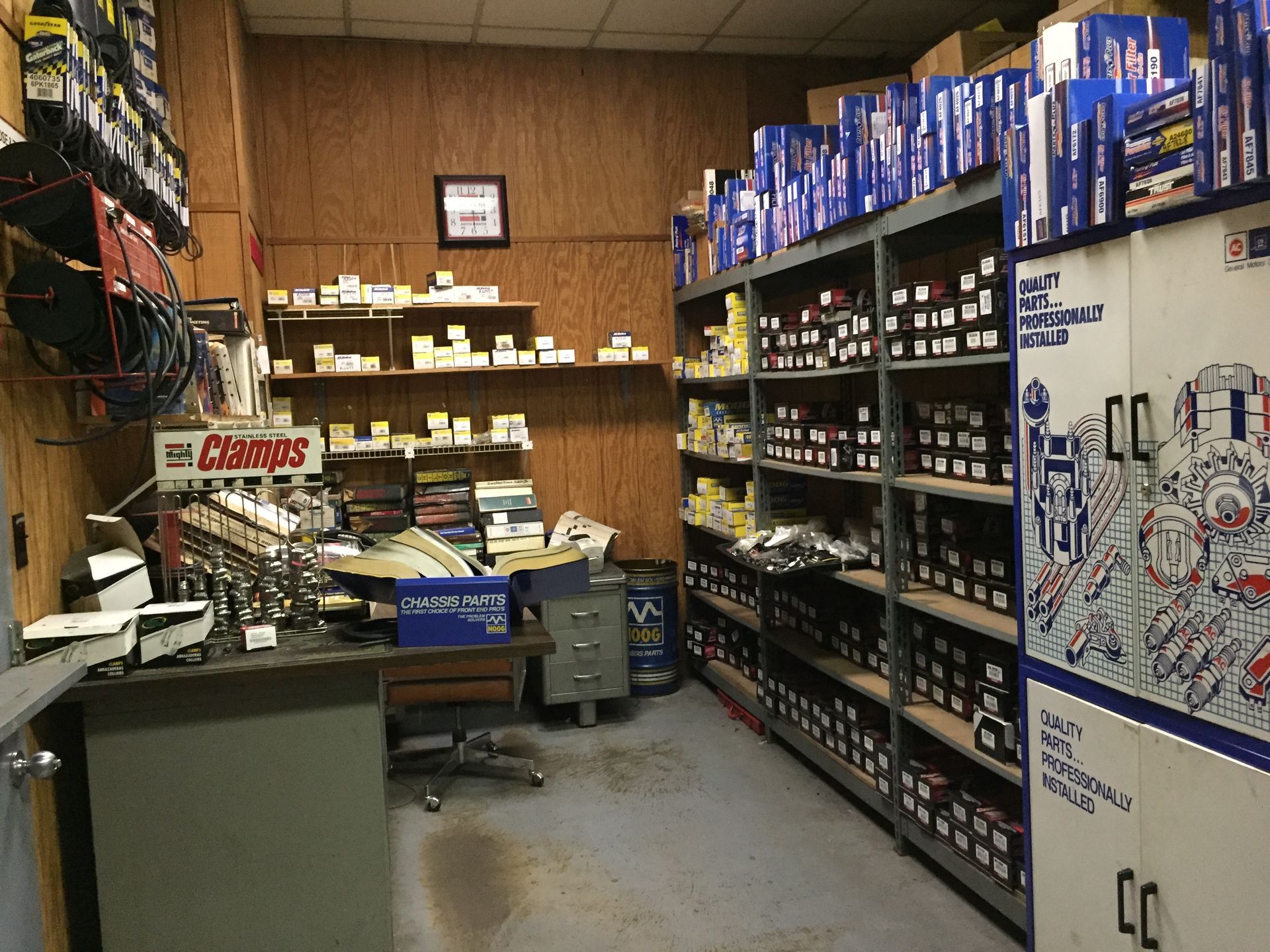 Small auto parts shop aisle with shelves of boxed parts and tools in a narrow wooden room
