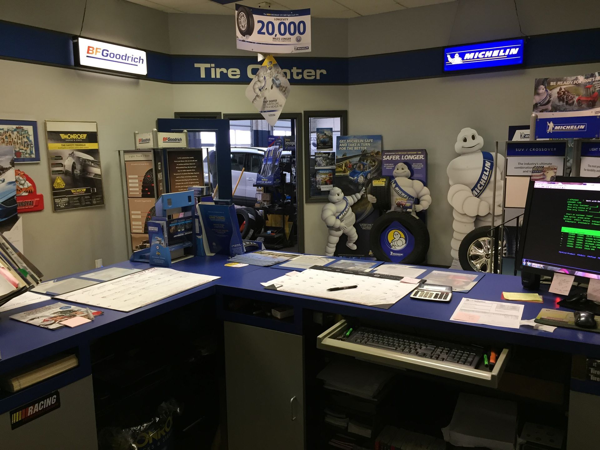 Indoor retail booth with blue counters, signs, monitors, and mannequins in a showroom-like space