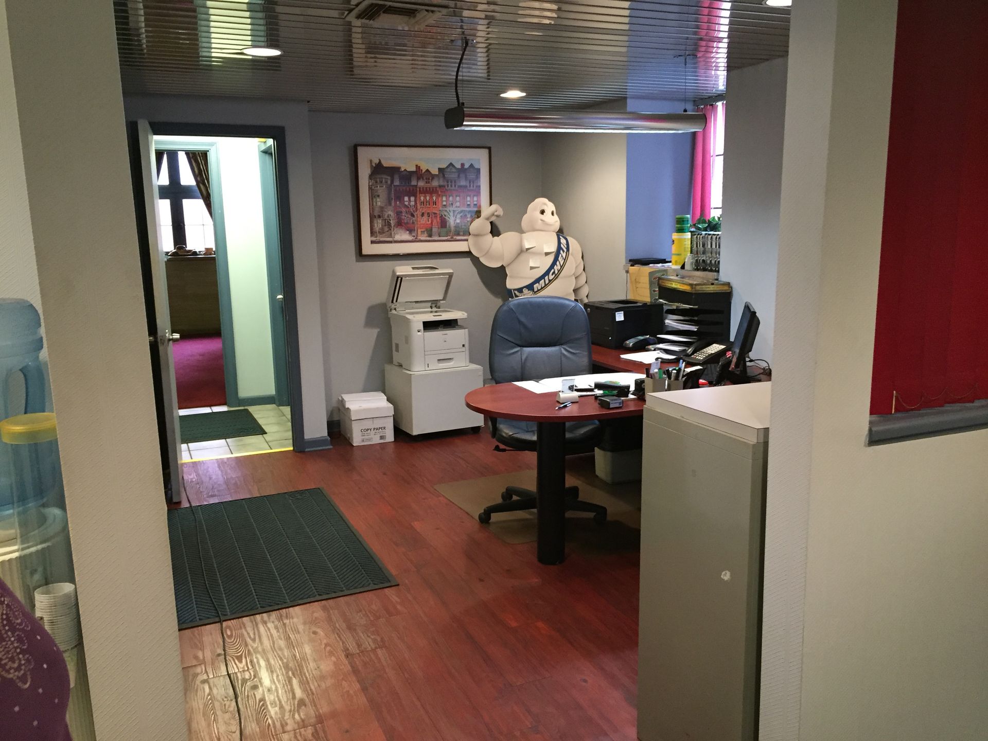 Office lobby with a desk, computer, chairs, and a white mannequin near the back wall.