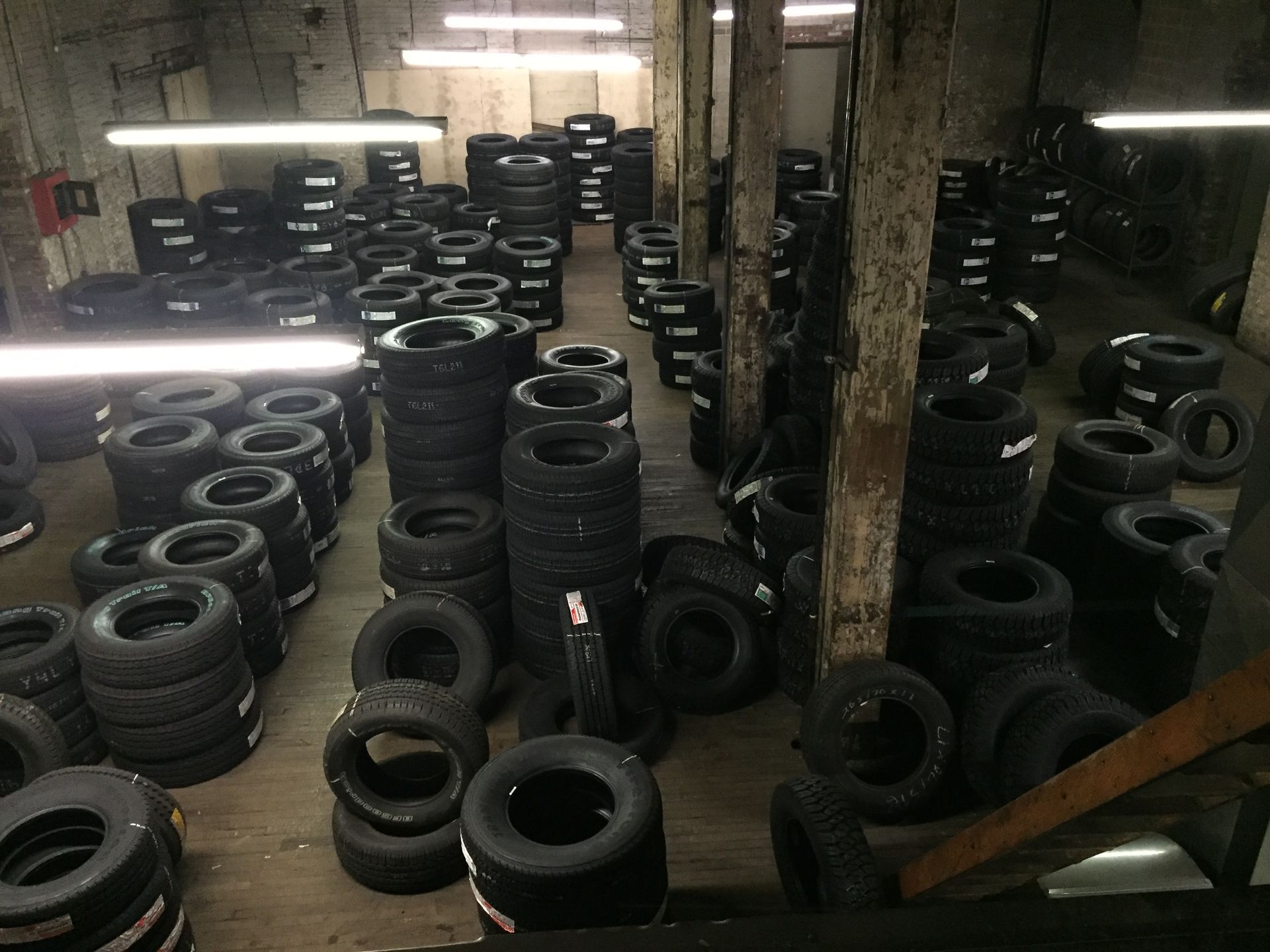 Large warehouse filled with stacks of black tires under fluorescent lights