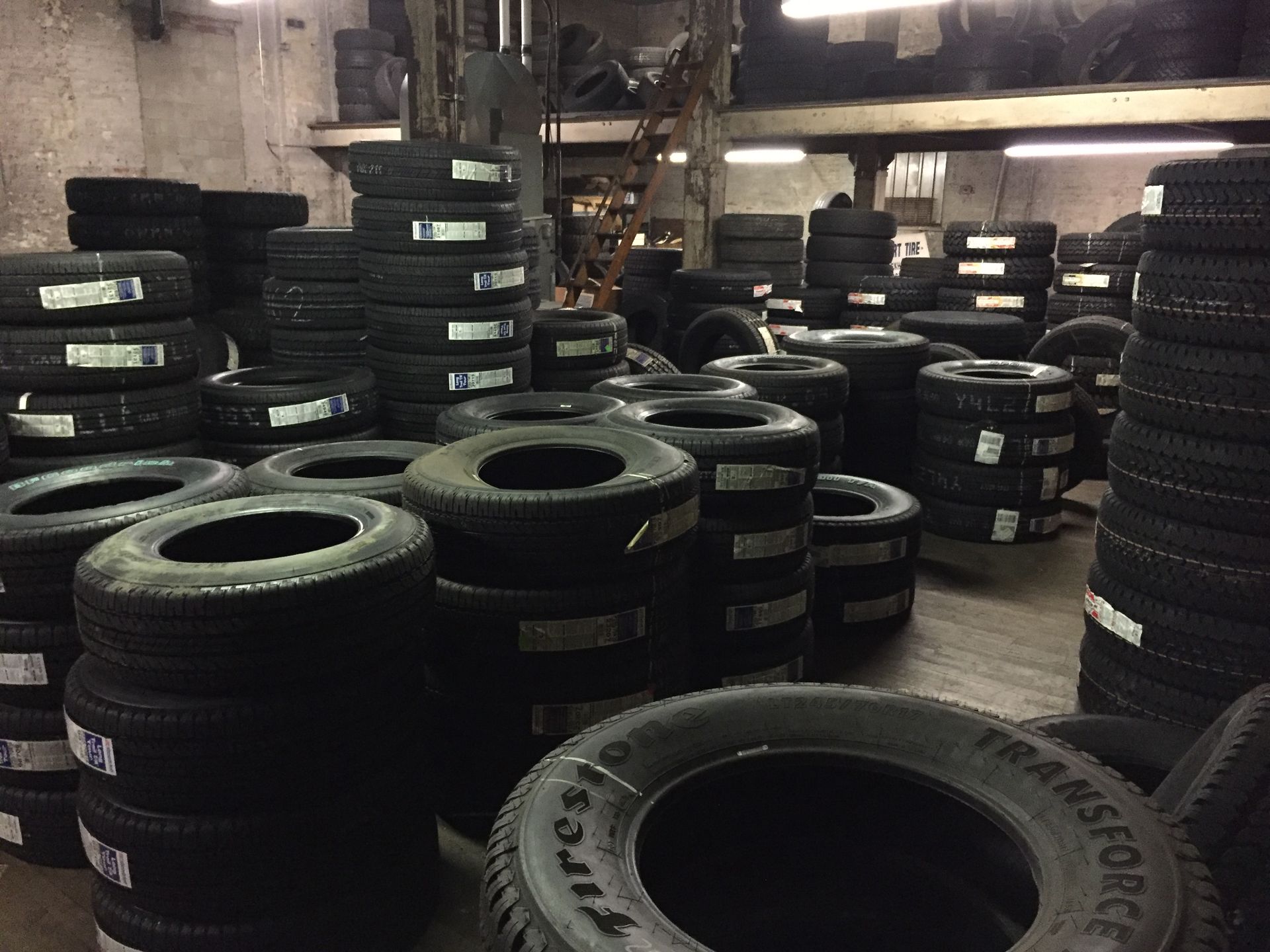 Stacks of black tires stored in a warehouse with dim lighting.
