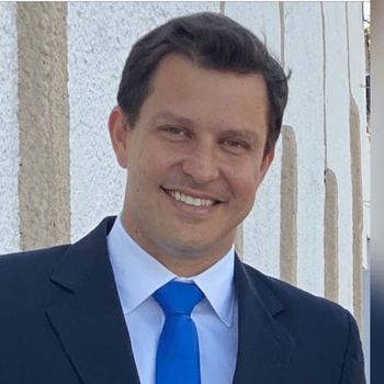 Um homem de terno e gravata está sorrindo para a câmera