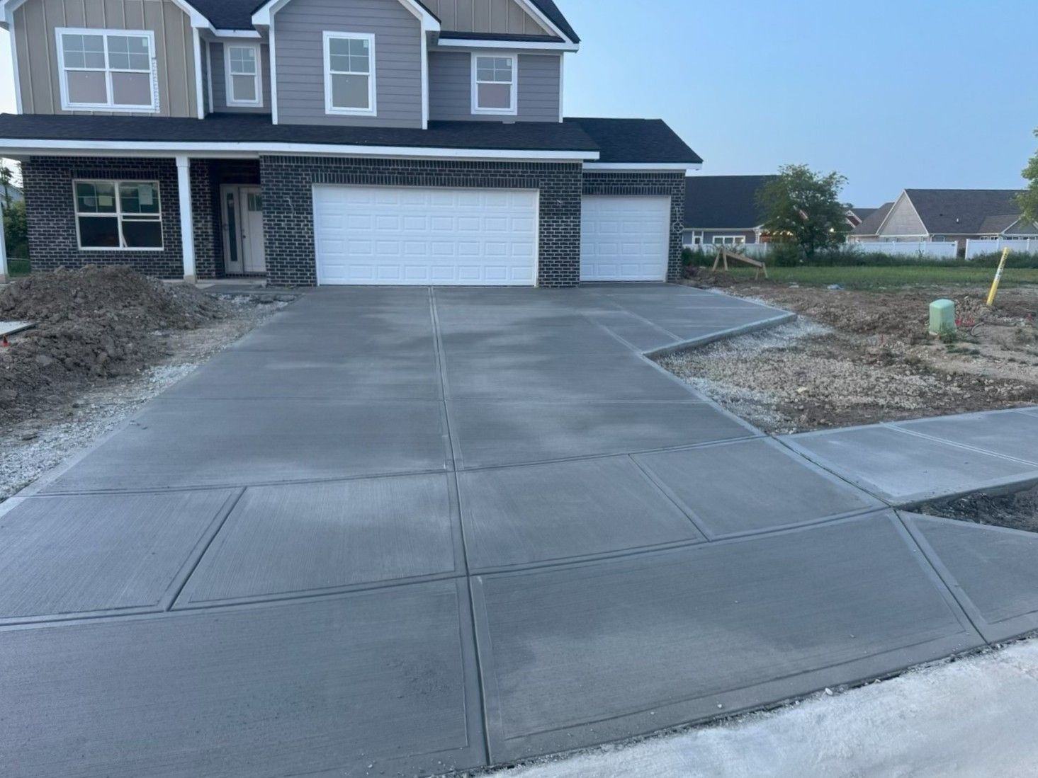 Suburban house with a wide concrete driveway and attached garage on a cloudy day