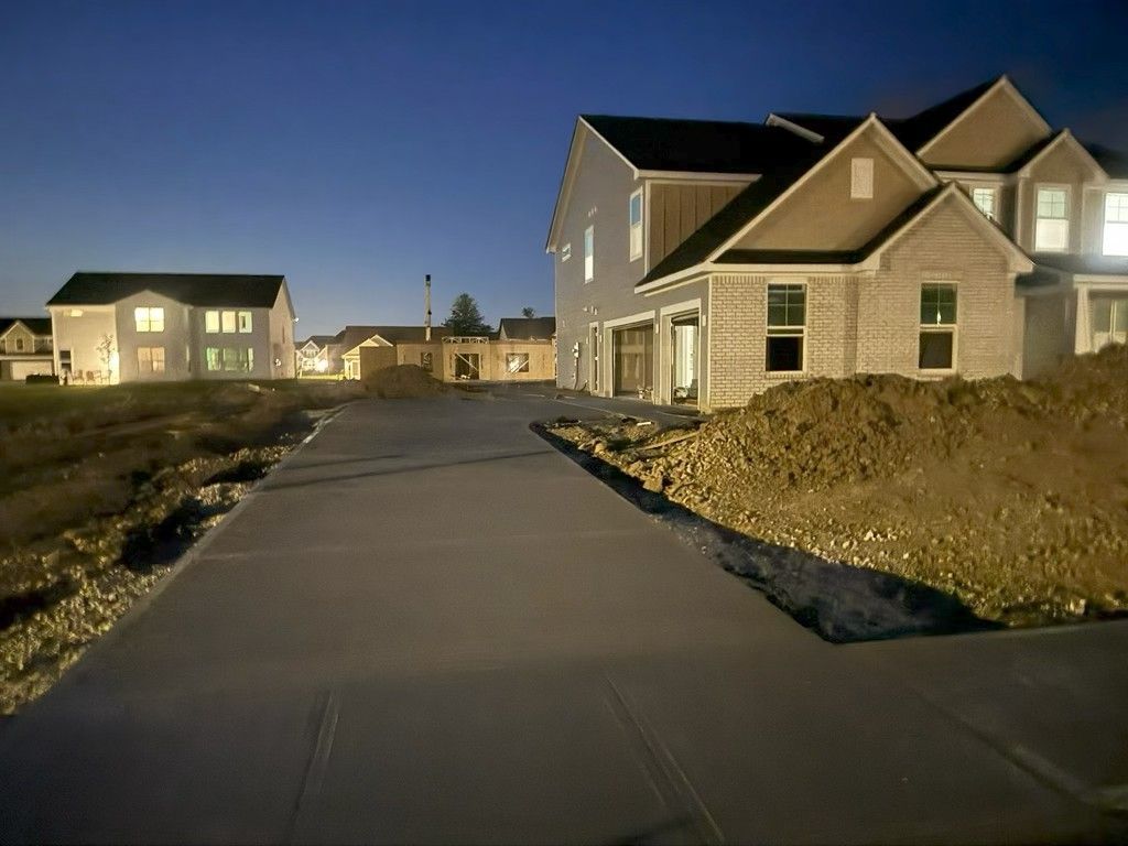 Suburban neighborhood street at dusk with newly built houses and a paved sidewalk under a clear sky