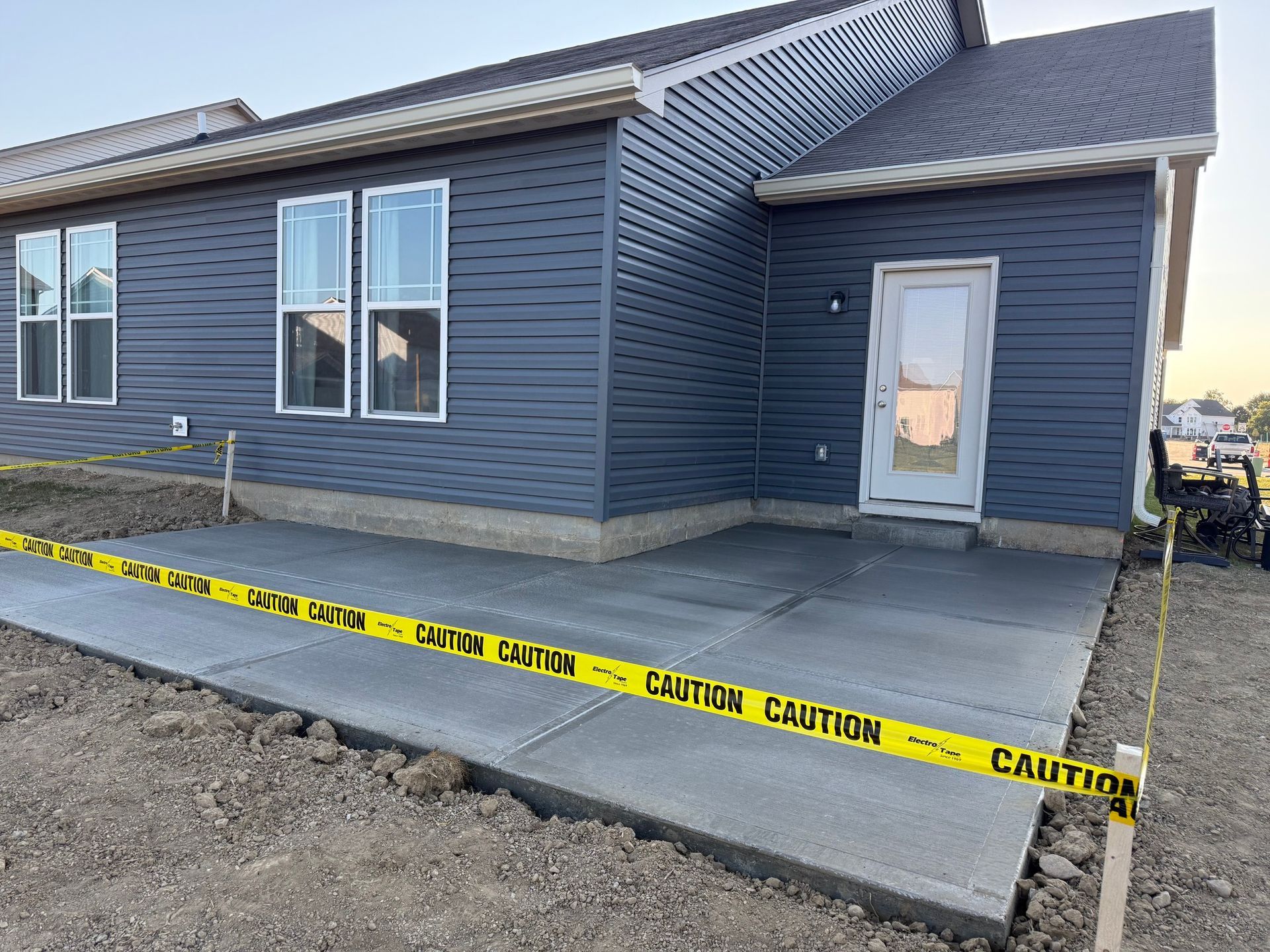 New house with blue siding and a concrete walkway behind caution tape.