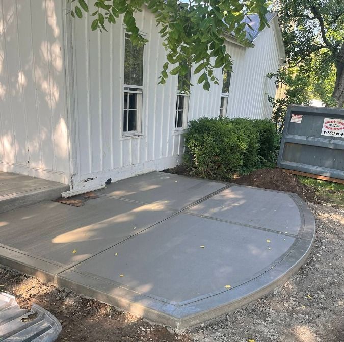 Concrete ramp leading to a white building entrance beside windows and bushes